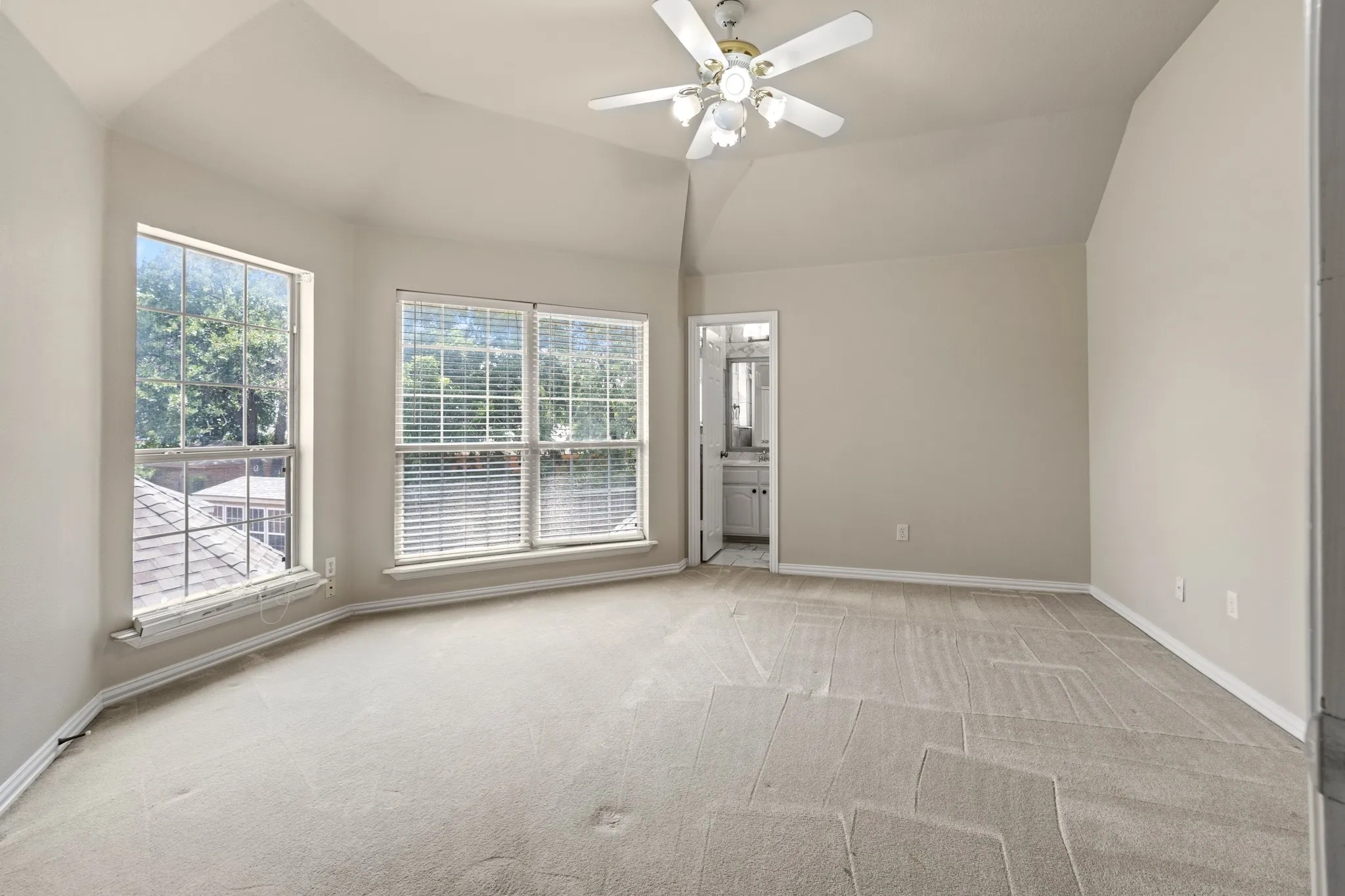 upstairs primary bedroom Carpeted empty room featuring ceiling fan and vaulted ceiling