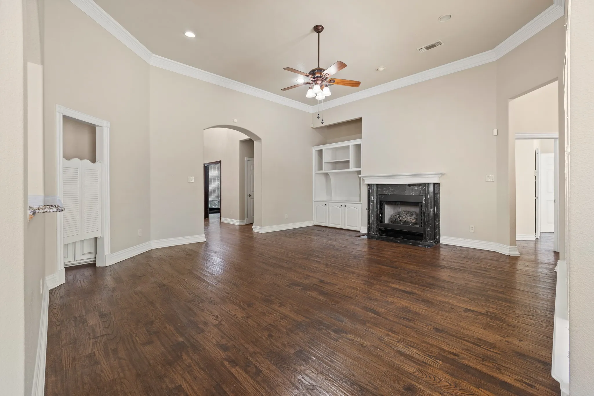 Unfurnished living room with ceiling fan, dark hardwood / wood-style flooring, ornamental molding, and a high end fireplace