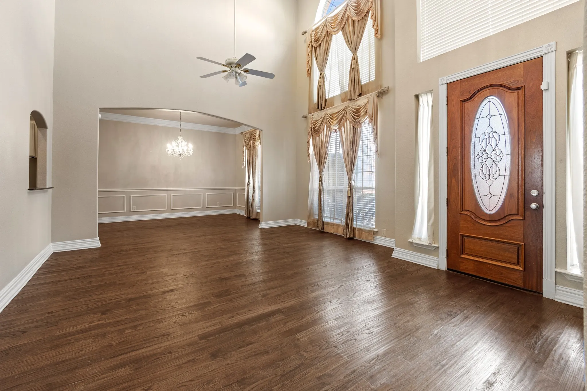 Foyer entrance with crown molding, a high ceiling, dark hardwood / wood-style floors, and ceiling fan with notable chandelier