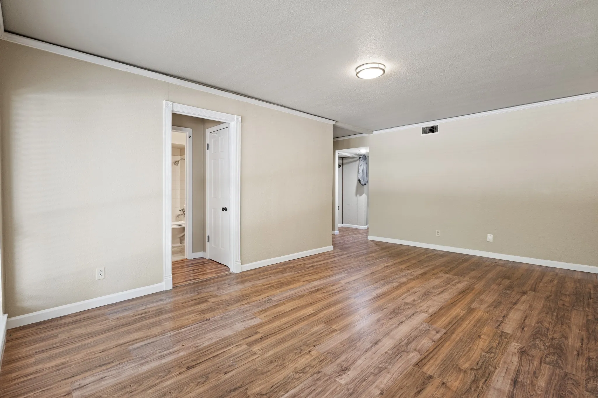 Empty room with wood finished floors, ornamental molding, and a textured ceiling