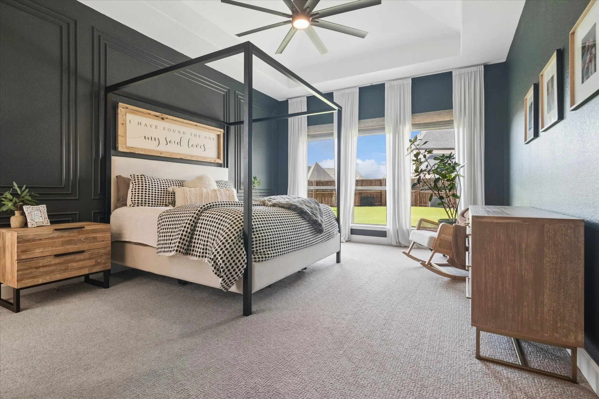 Step into your serene primary bedroom with custom accent wall, oversized windows to the backyard, tray ceiling and ceiling fan.