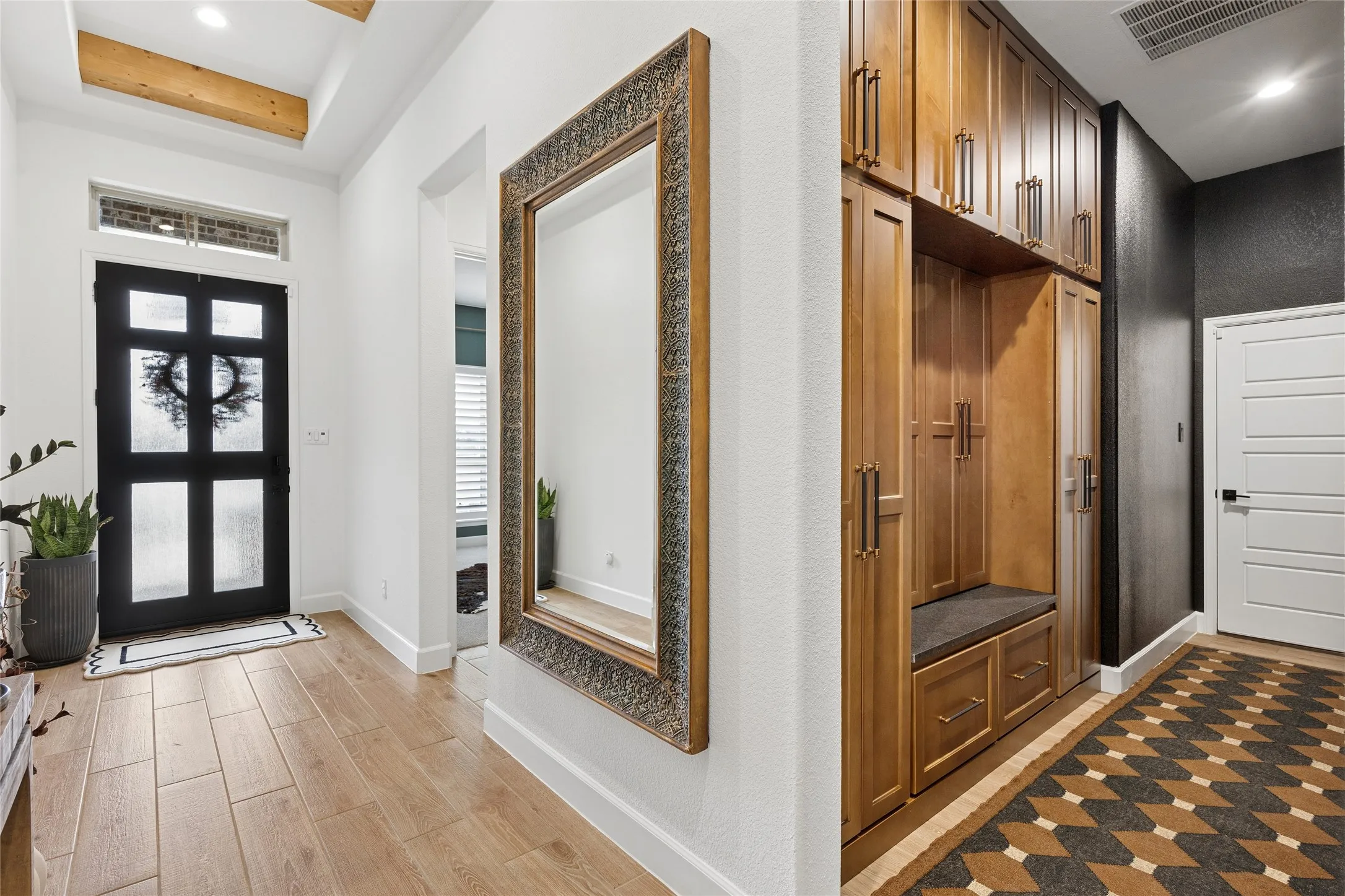 Welcome Home! Iron with privacy glass front door, transom window above for even more natural light. Over sized entrance with beamed ceiling. Custom mud room with door to the garage.