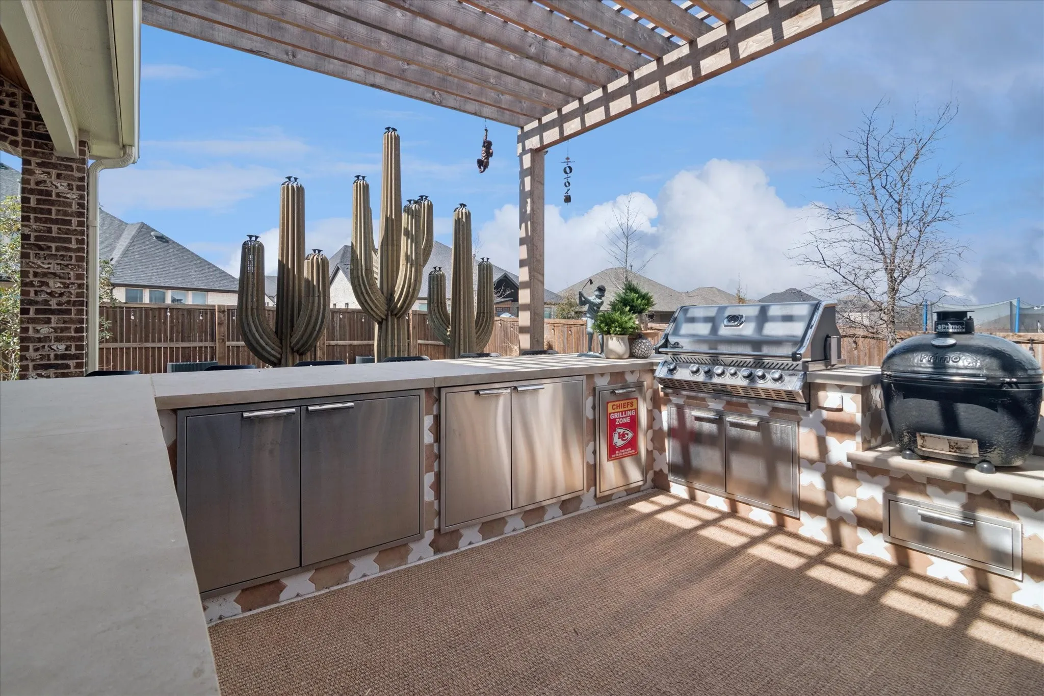 Outdoor kitchen with ample storage, built in grill, egg smoker, refrigerator, arbor.