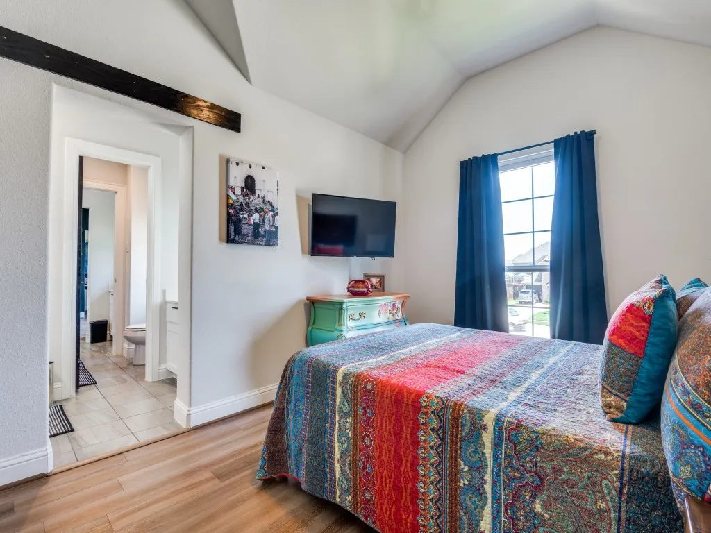 Bedroom featuring vaulted ceiling, wood finished floors, and connected bathroom