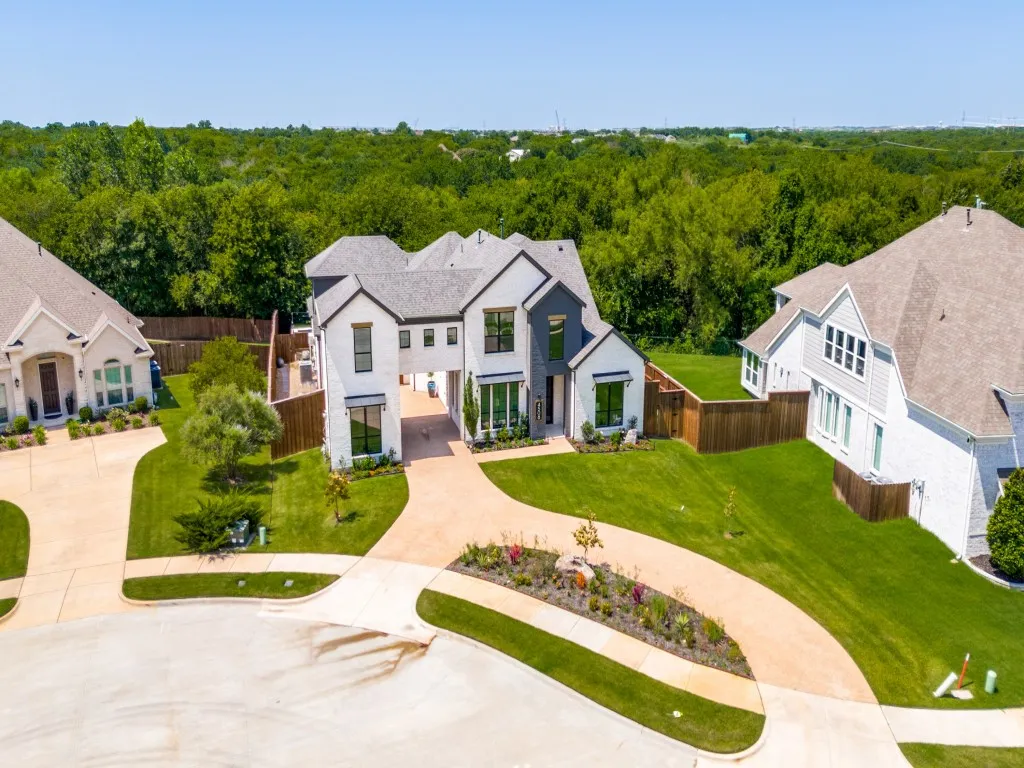 View of front of home with a view of trees and curved driveway