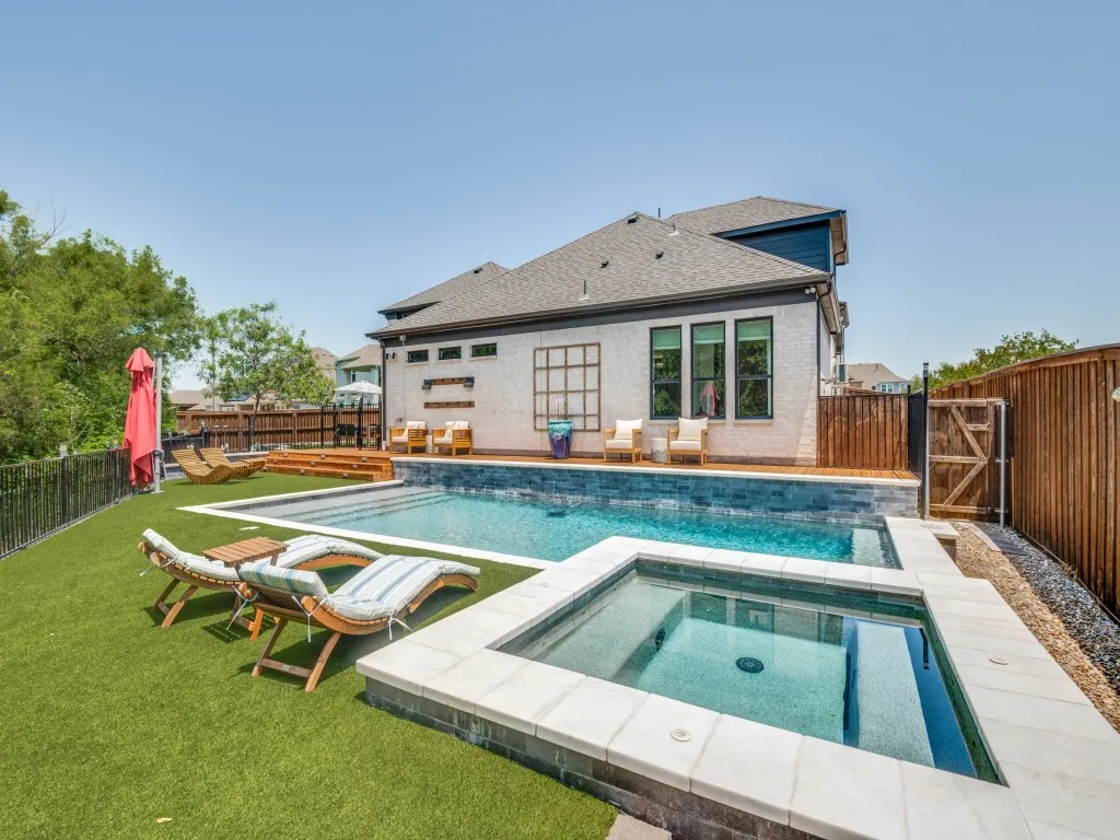 View of swimming pool featuring an in-ground hot tub, a fenced backyard, and a gate