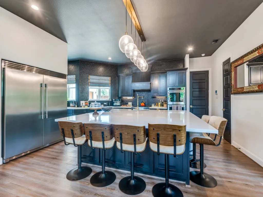 Kitchen with appliances with stainless steel finishes, light wood finished floors, backsplash, a kitchen bar, and recessed lighting