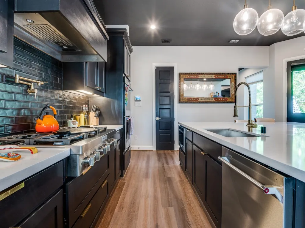 Kitchen with extractor fan, light countertops, stainless steel appliances, light wood-style floors, and tasteful backsplash