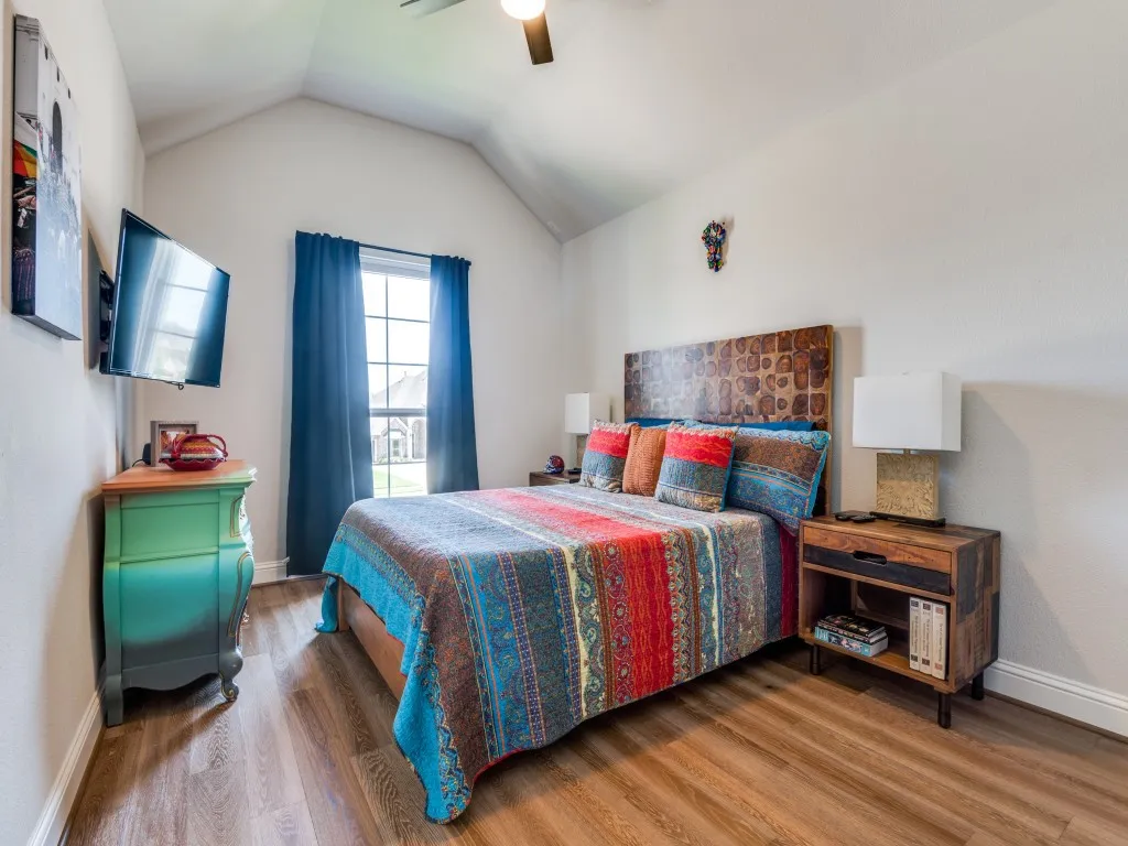 Bedroom featuring wood finished floors, lofted ceiling, and a ceiling fan