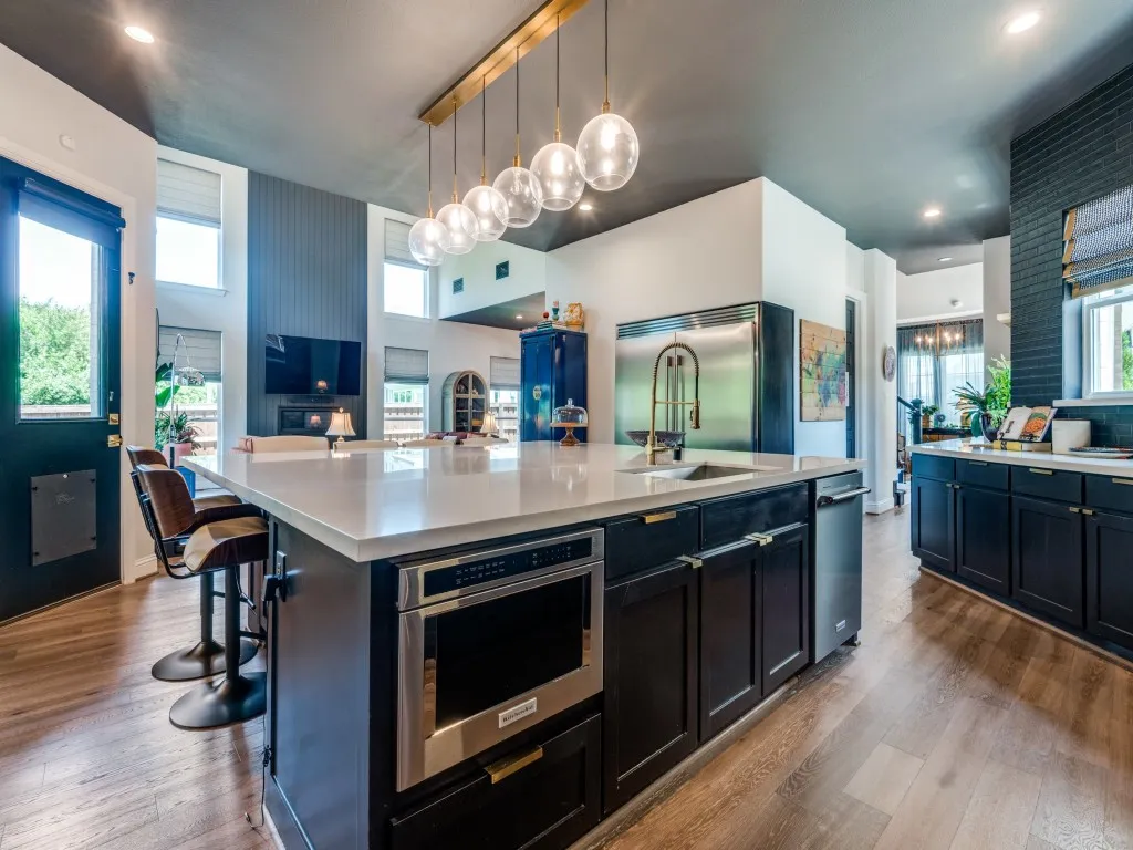 Kitchen featuring stainless steel appliances, light countertops, open floor plan, wood finished floors, and a large island