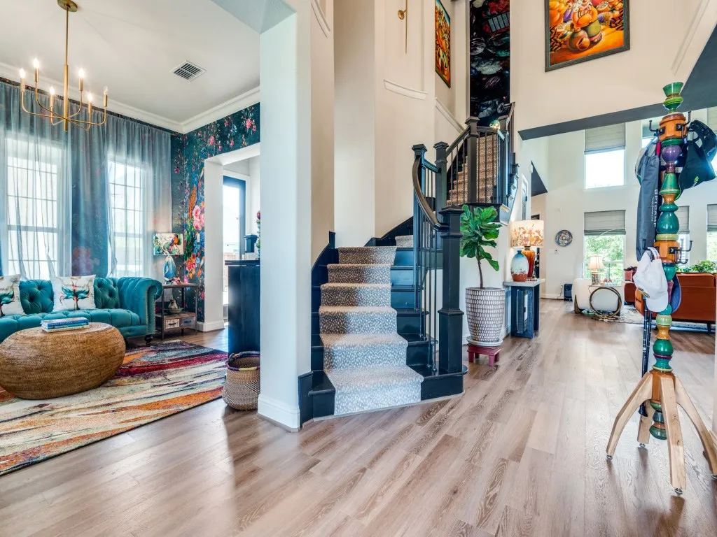 Entryway featuring a chandelier, stairs, wallpapered walls, crown molding, and wood finished floors