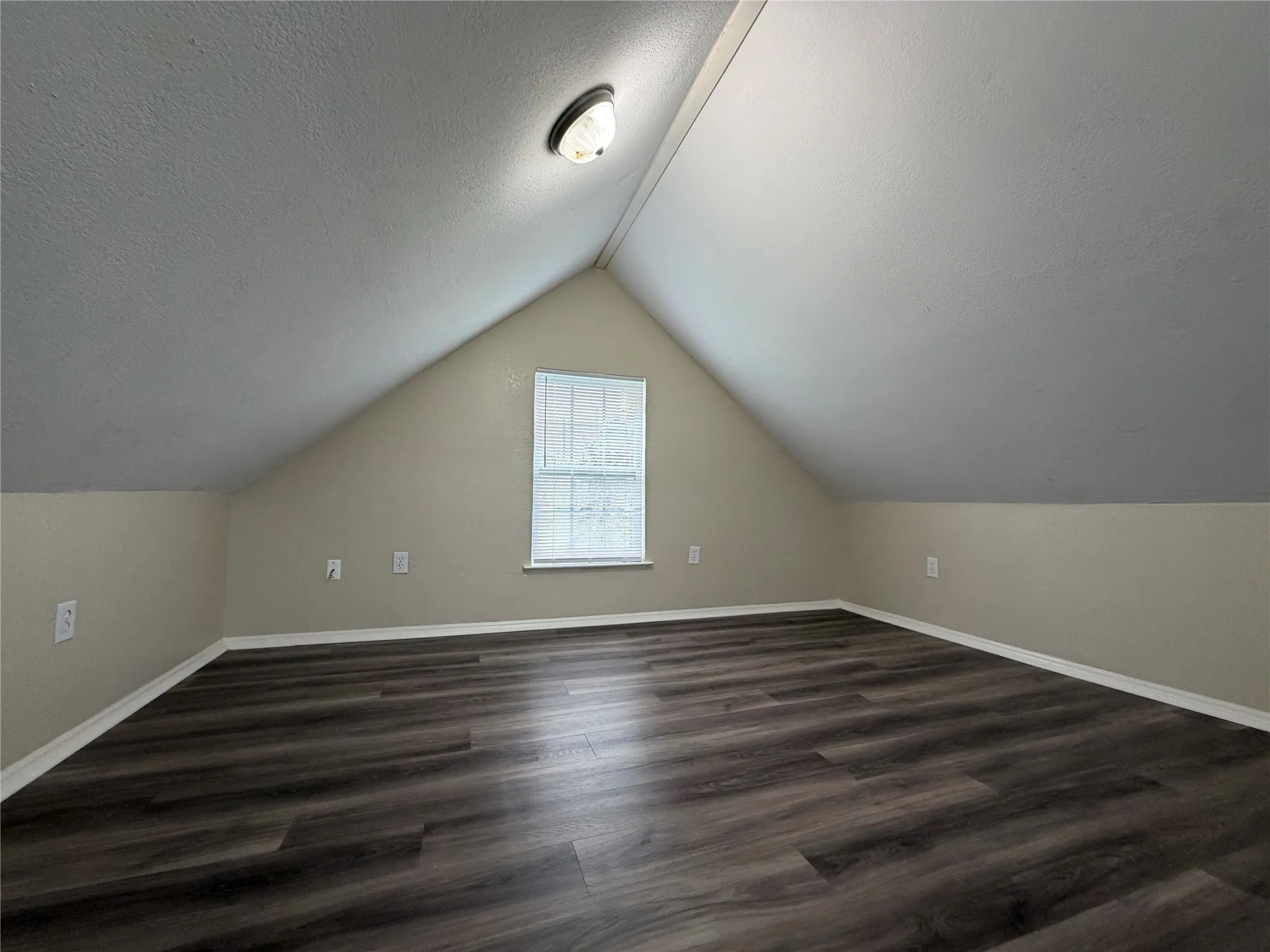 Bonus room with dark wood-style flooring and a textured ceiling