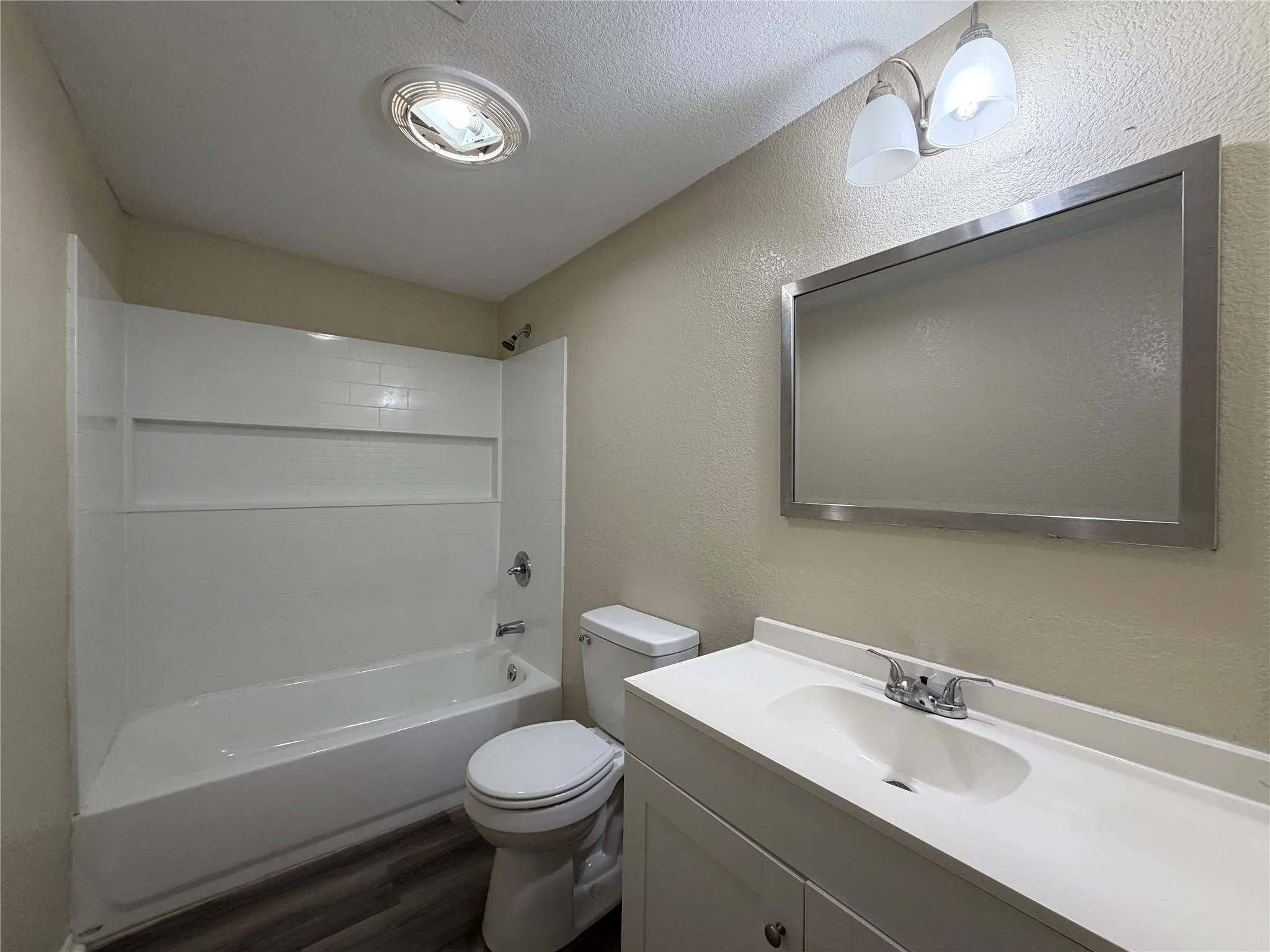 Full bathroom with vanity, washtub / shower combination, a textured wall, dark wood finished floors, and a textured ceiling
