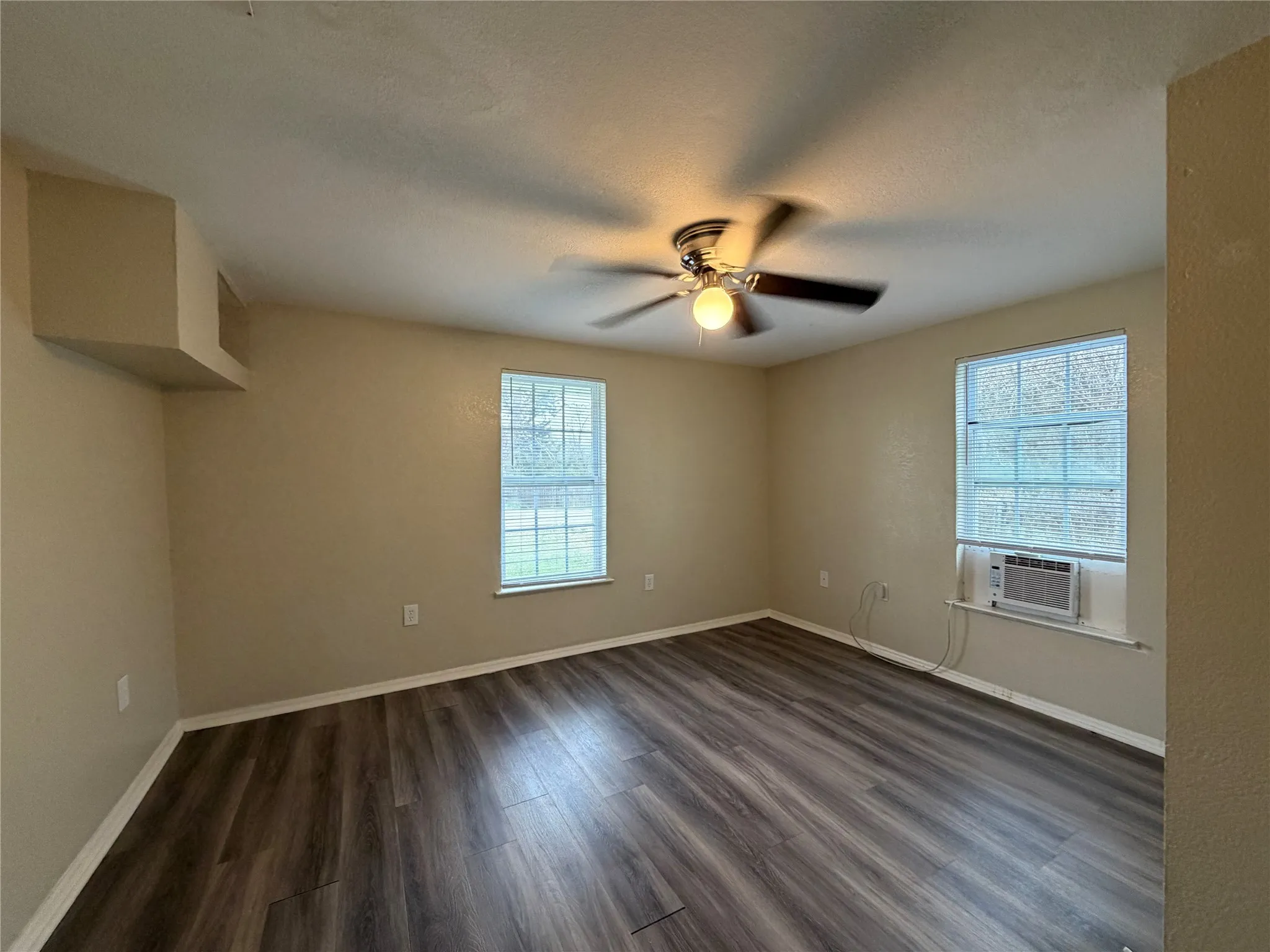 Spare room featuring dark wood finished floors, a ceiling fan, a textured ceiling, and cooling unit
