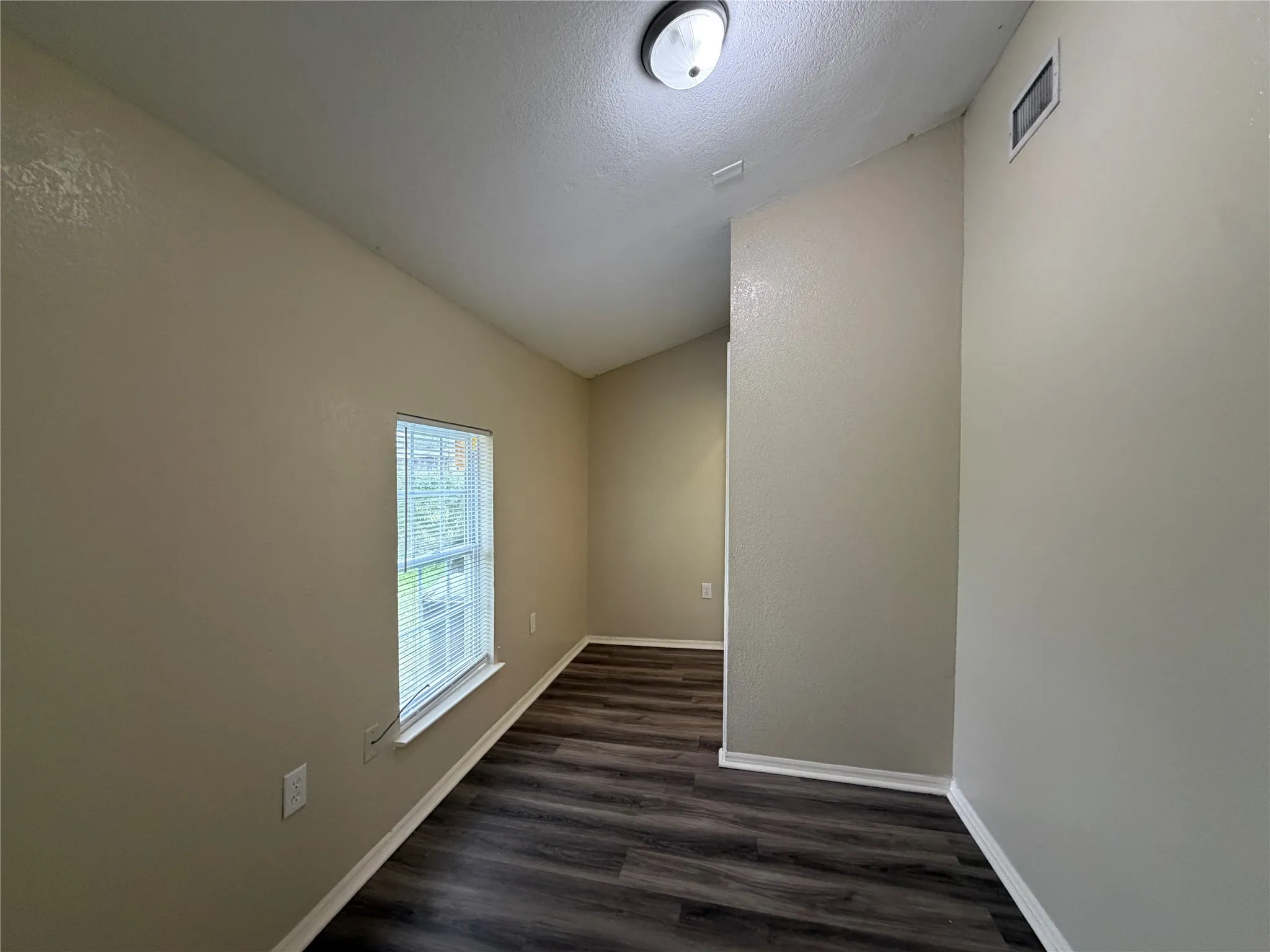 Spare room with baseboards and dark wood-type flooring