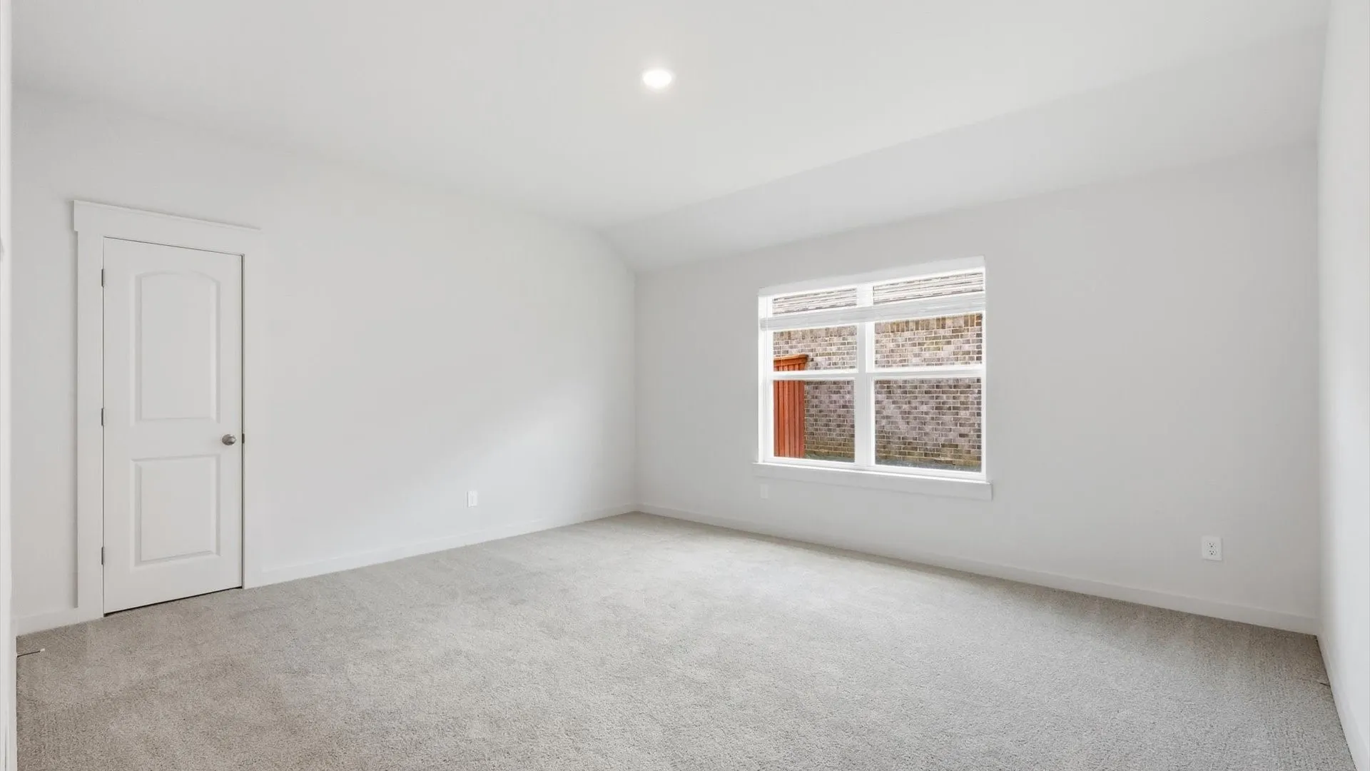 Carpeted room with a large window and a single panel door