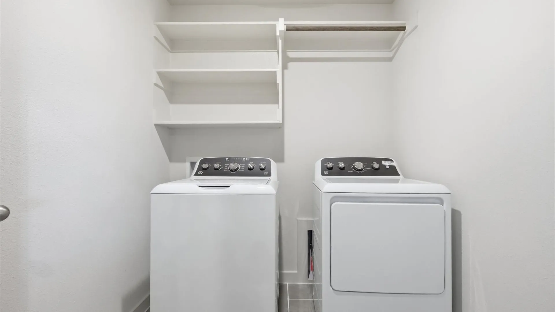 Dedicated laundry area featuring white walls, open shelving, and a hanging rod