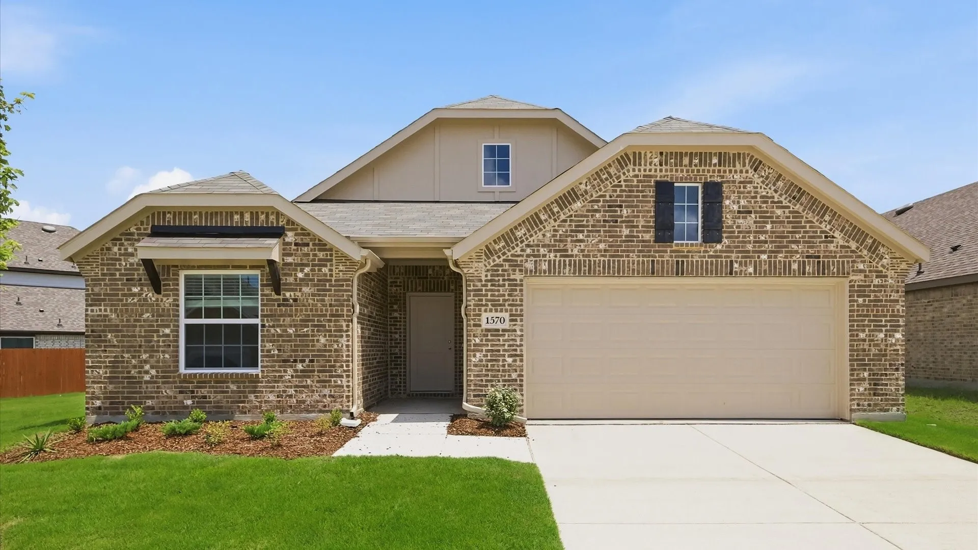 Traditional brick exterior featuring a two-car garage, front walk, and manicured lawn