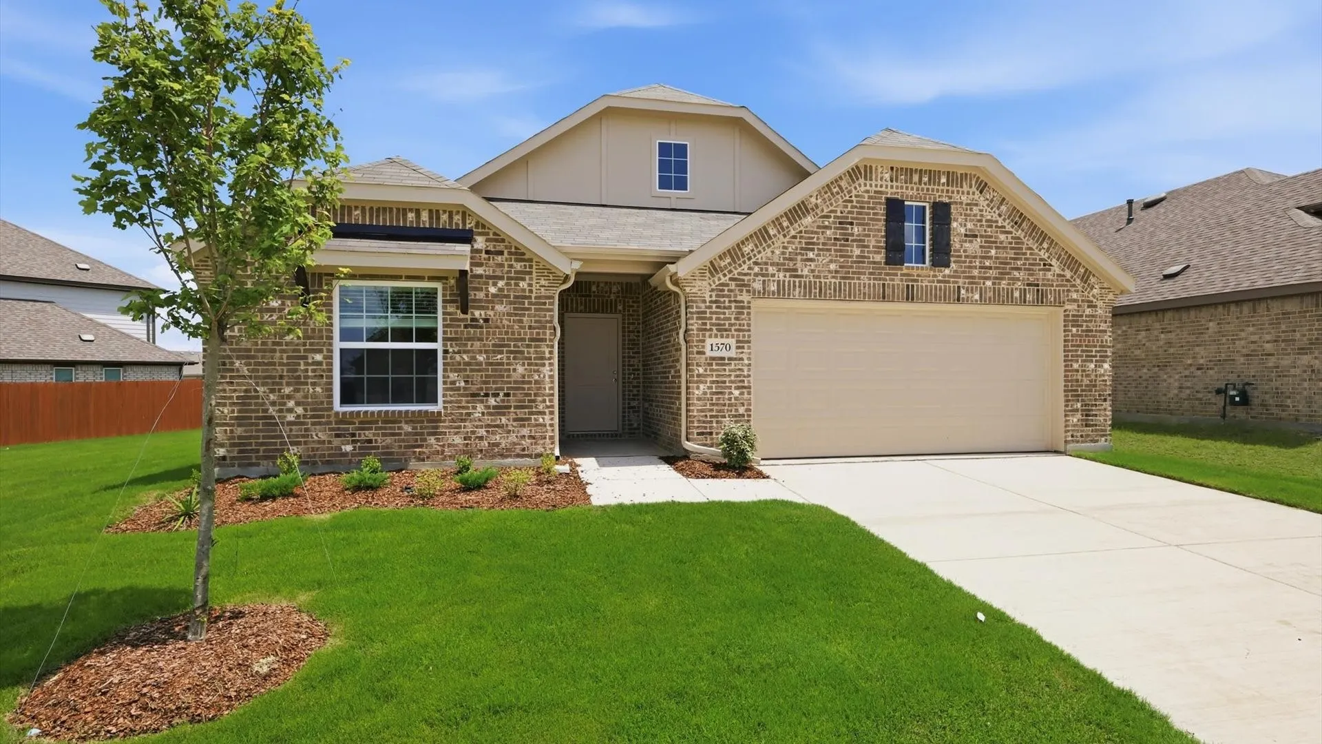 Brick facade residence featuring a two-car garage, mature landscaping, and an inviting entryway