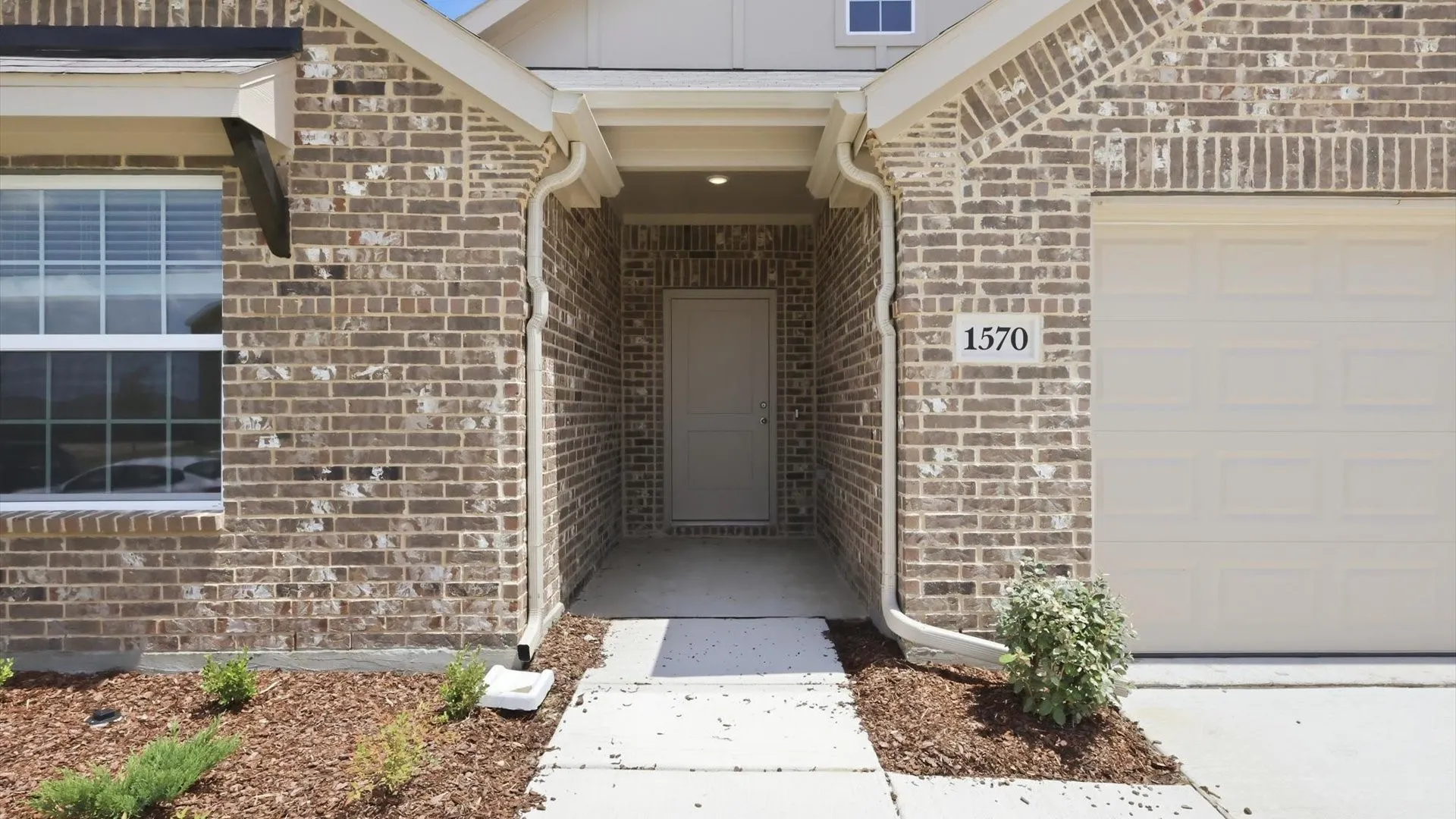 Brick exterior featuring a recessed entry, covered porch, and attached garage