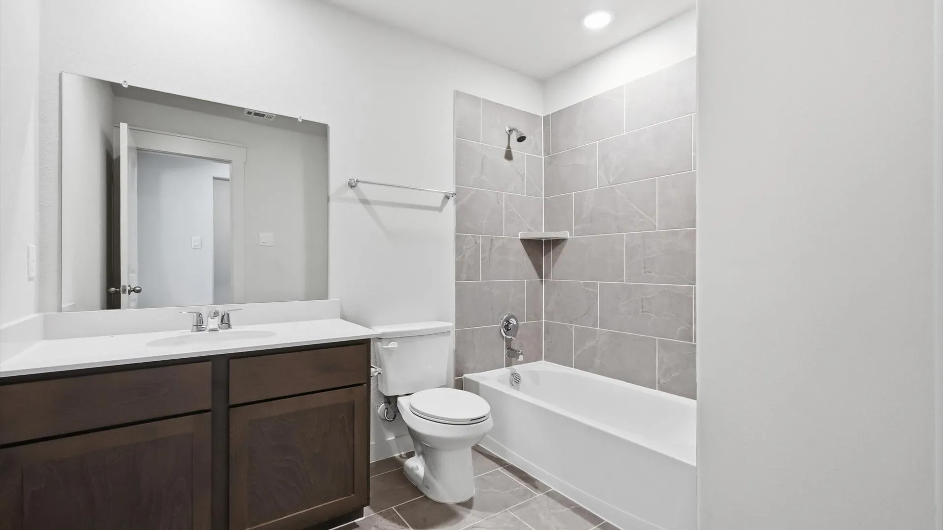 Bathroom featuring a wood-finish vanity with a white countertop, undermount sink, and a large wall-mounted mirror