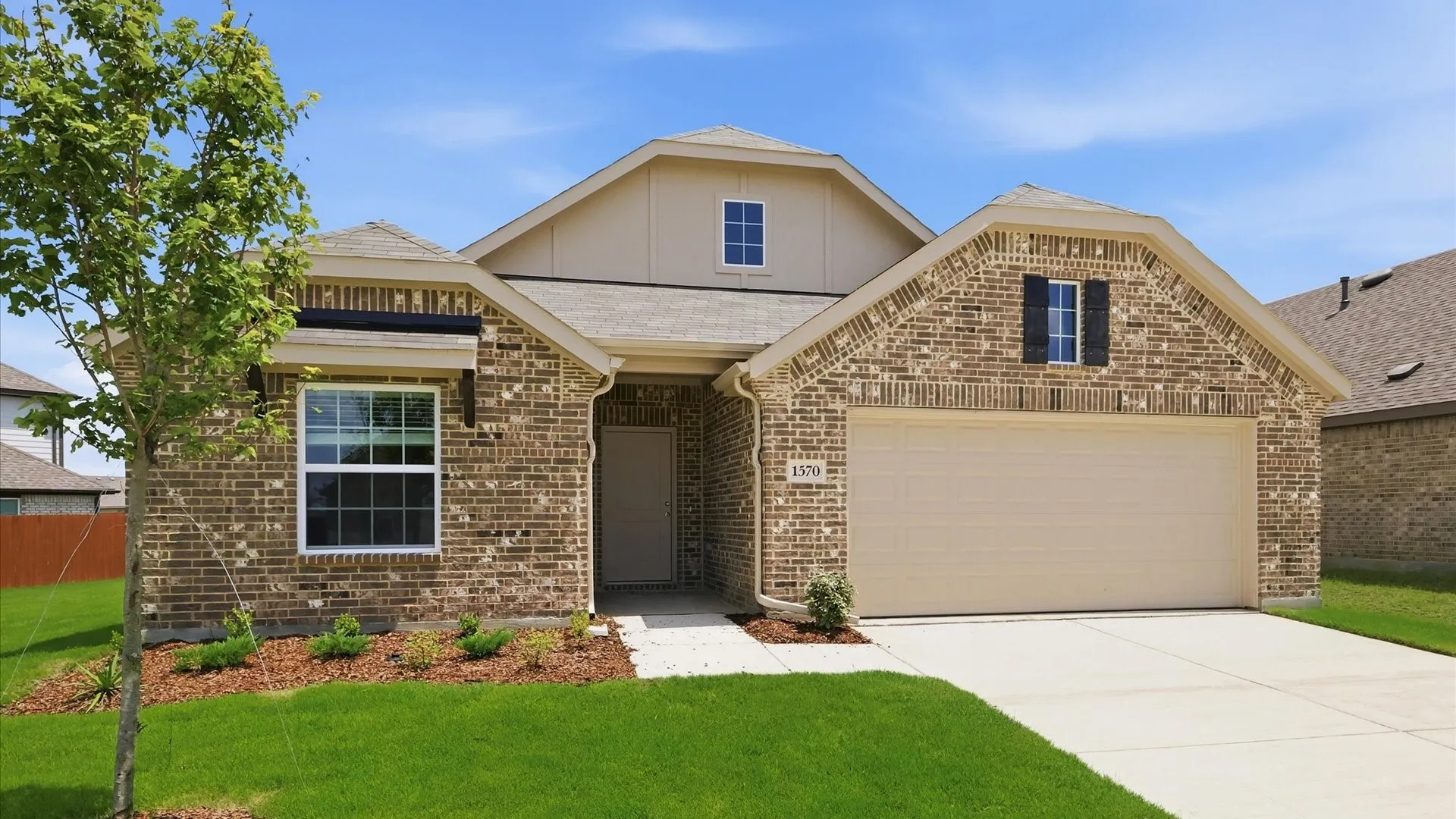 Traditional brick exterior featuring a front-facing attached garage, a covered entry, and a dormer window
