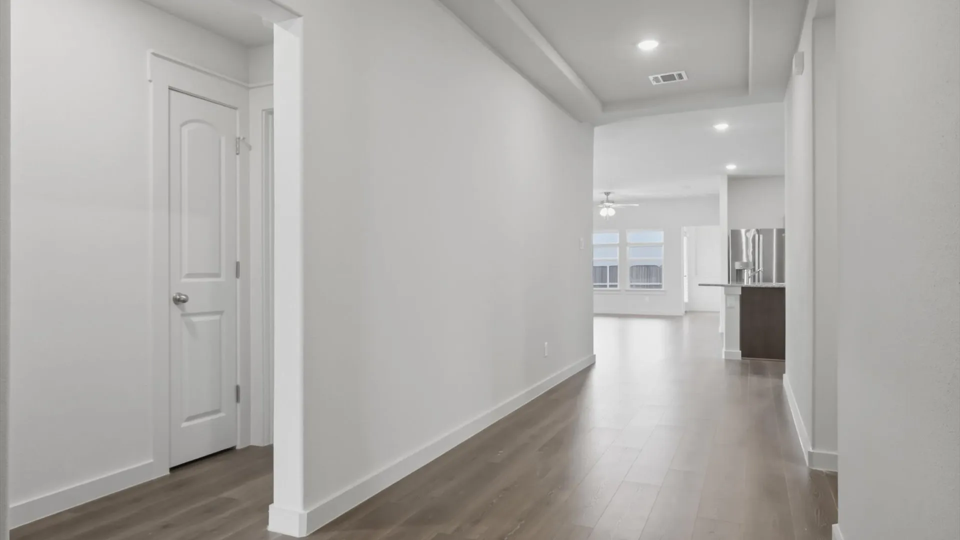 Long hallway featuring wood-finish flooring, recessed lighting, and a tray ceiling