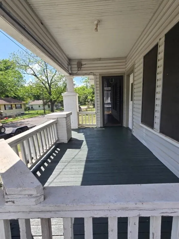 Covered front porch featuring wood flooring, painted railing, and an entry door with a screen