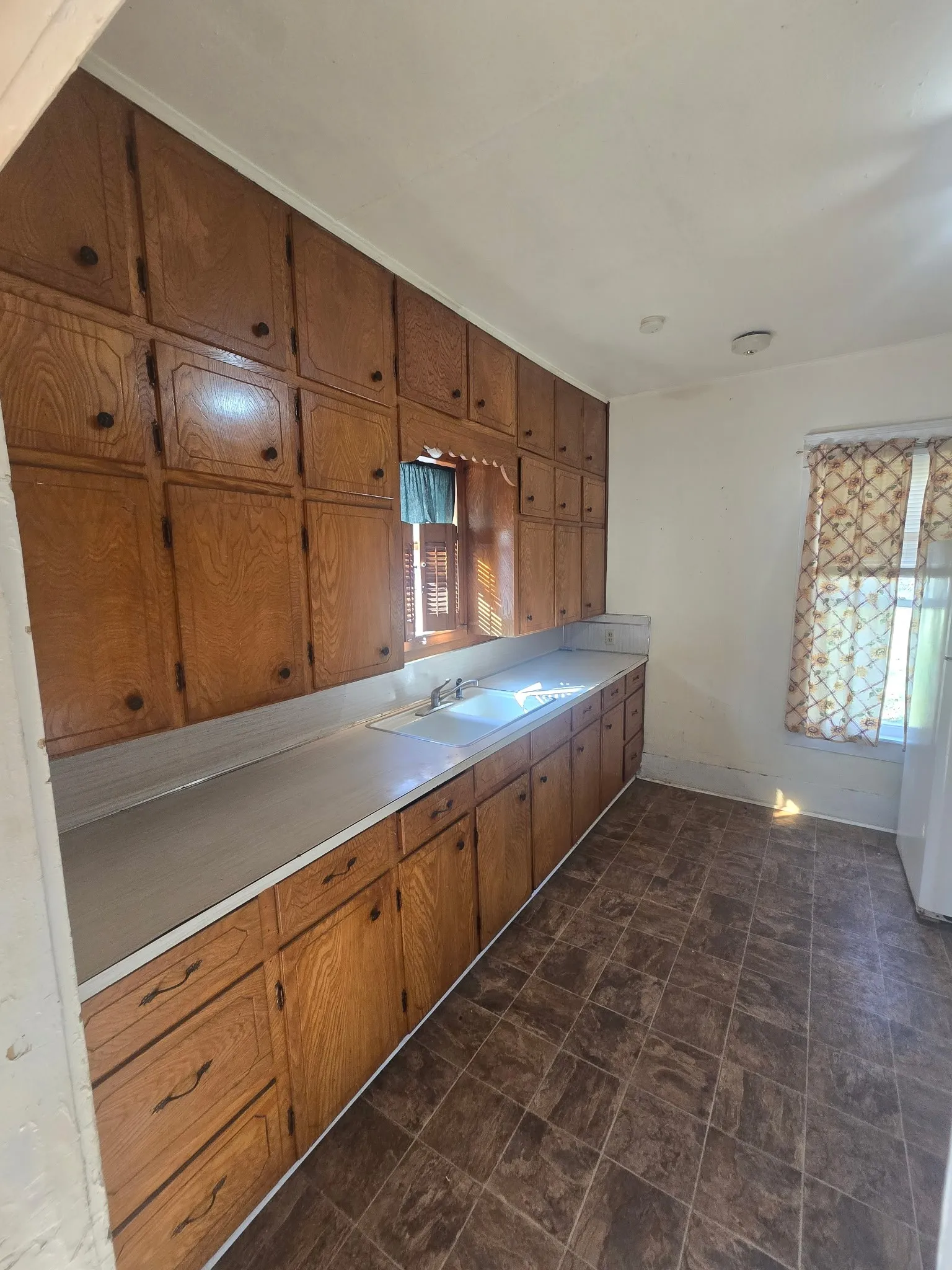 Kitchen featuring light countertops, wood finish cabinetry, stone finish flooring, and plenty of natural light