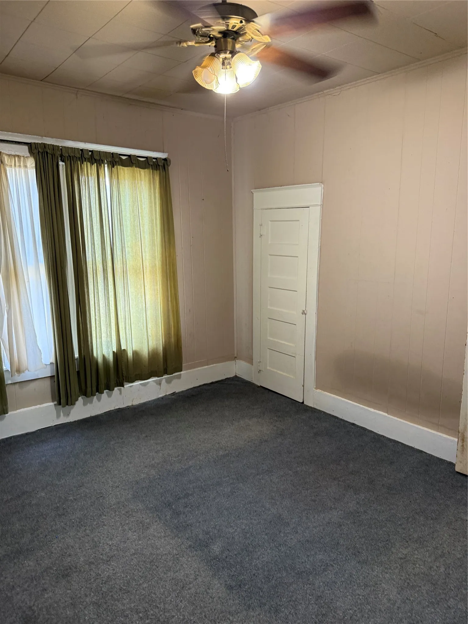 Room featuring a ceiling fan with integrated lighting, a paneled door, and baseboard trim