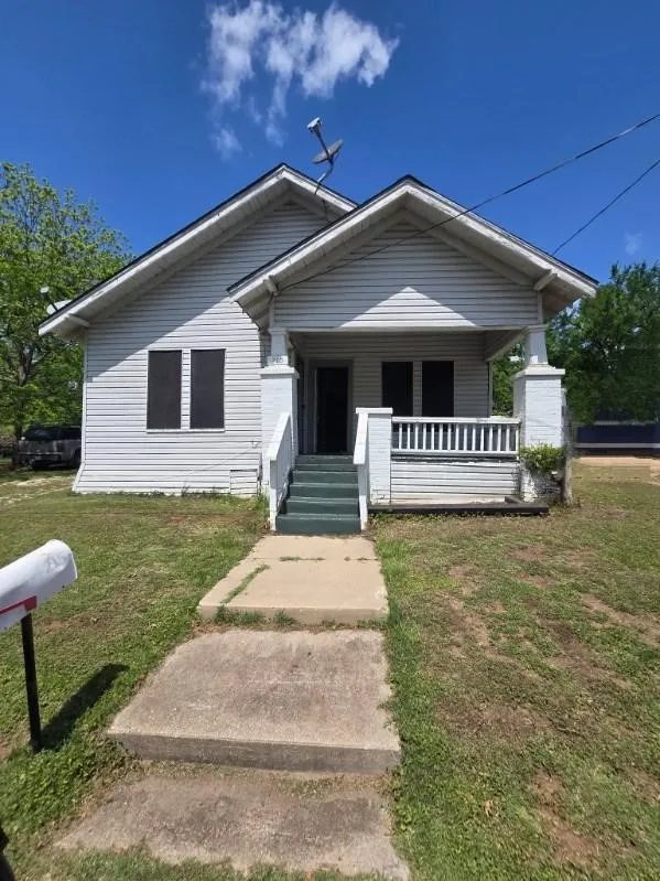 Traditional single-story residence featuring a front porch with white railings and columns