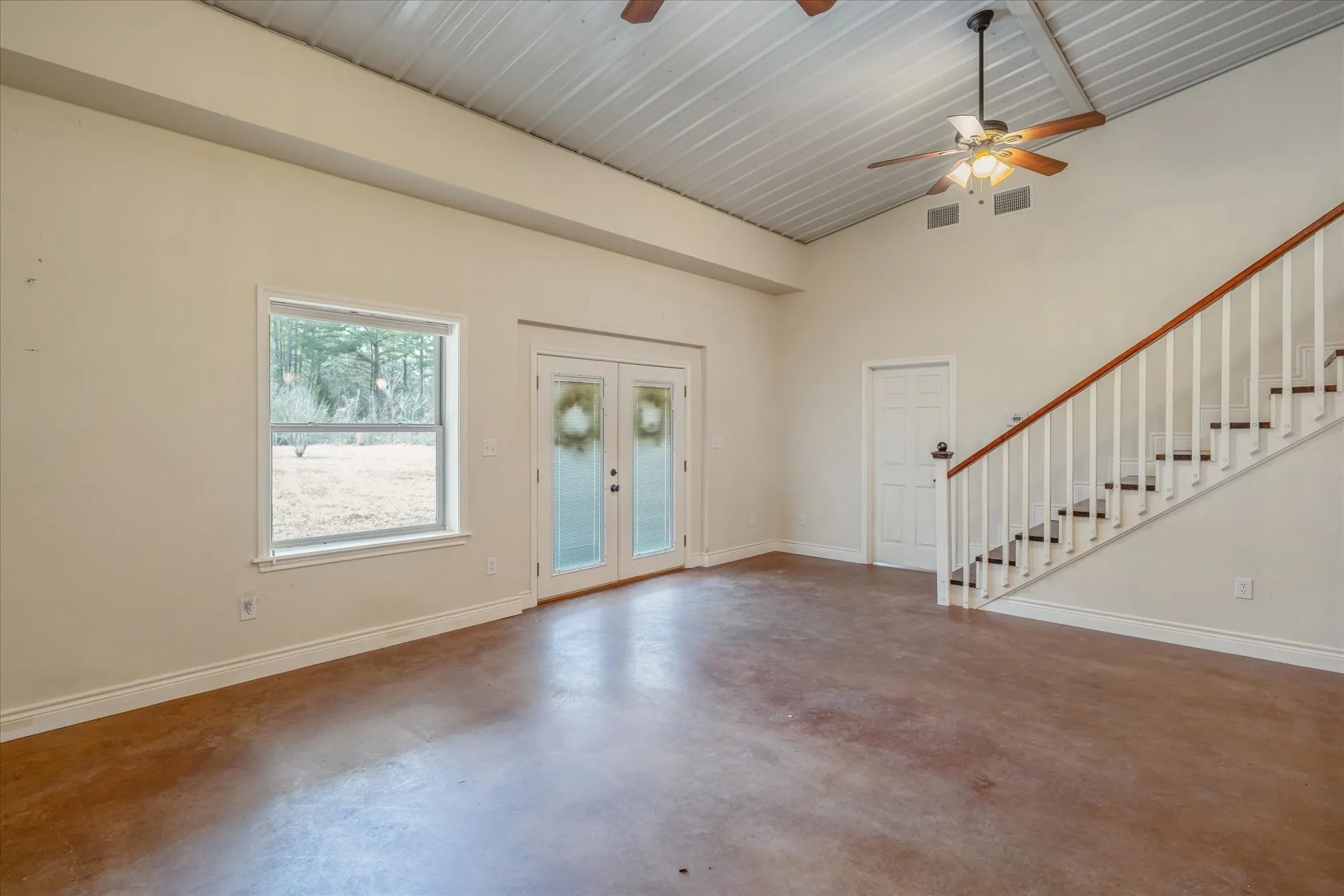 Entryway featuring french doors, a ceiling fan, finished concrete flooring, and vaulted ceiling