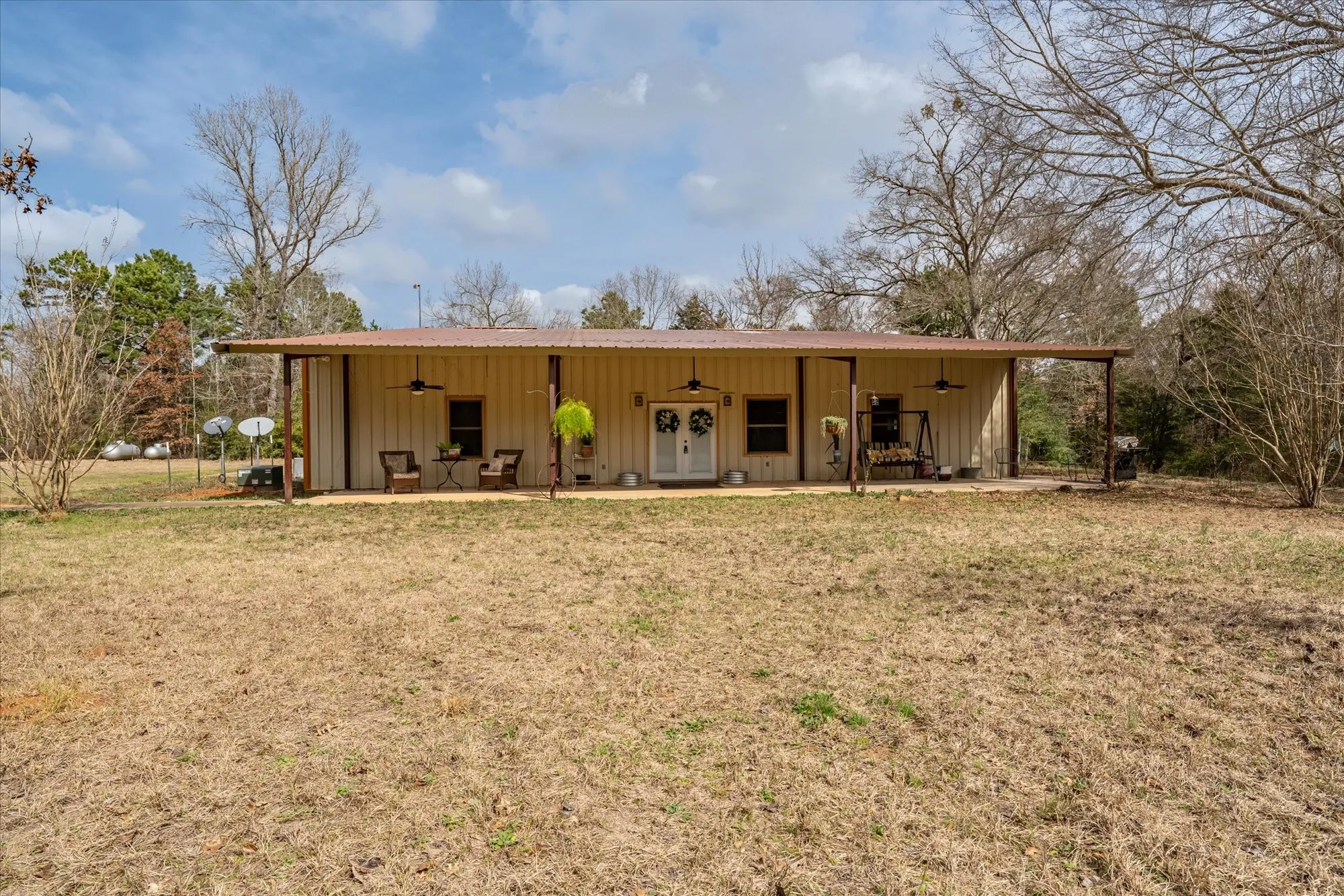 Front  view of property featuring ceiling fan, board and batten siding, and a yard