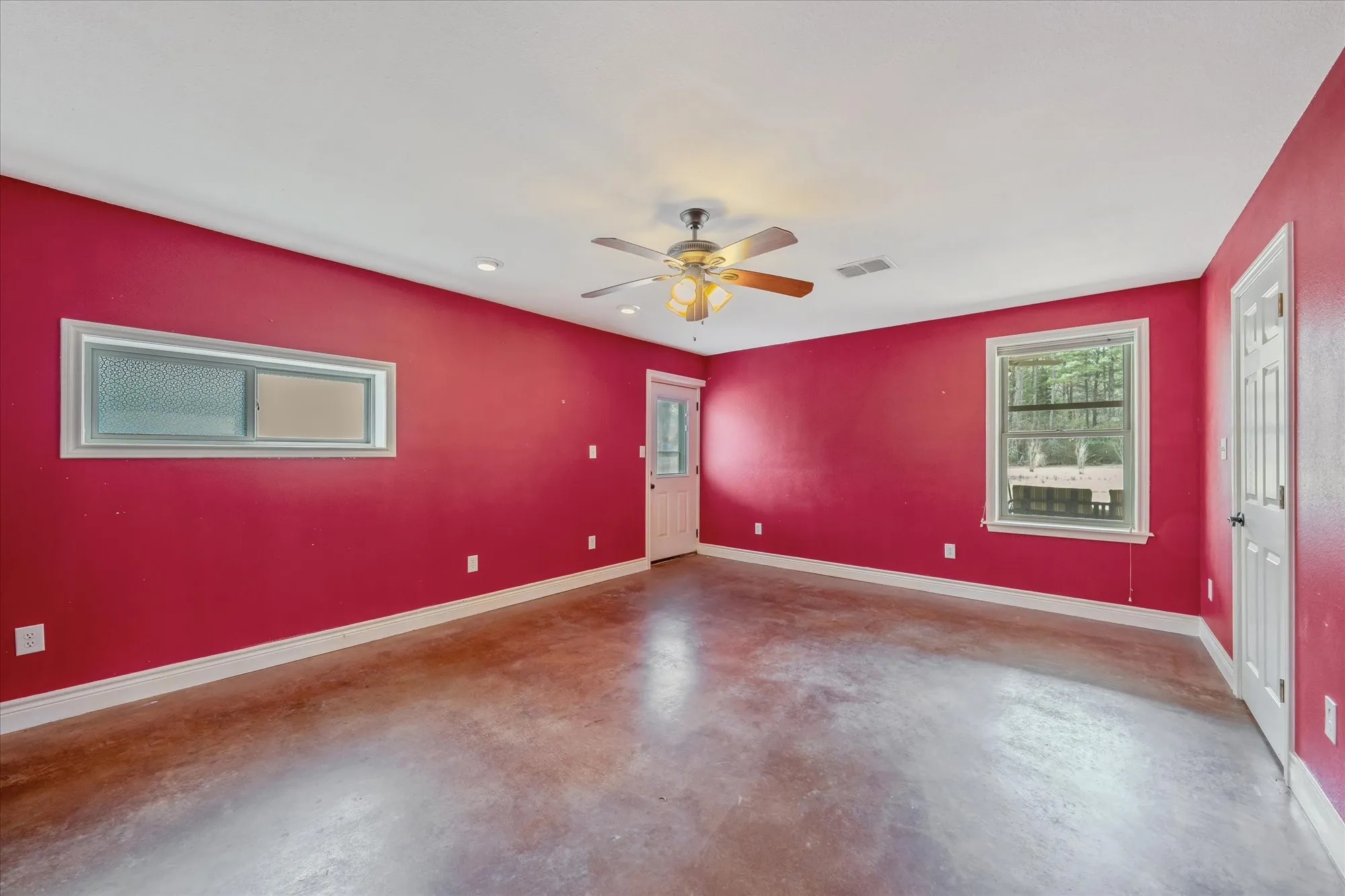 Unfurnished room with finished concrete flooring and ceiling fan