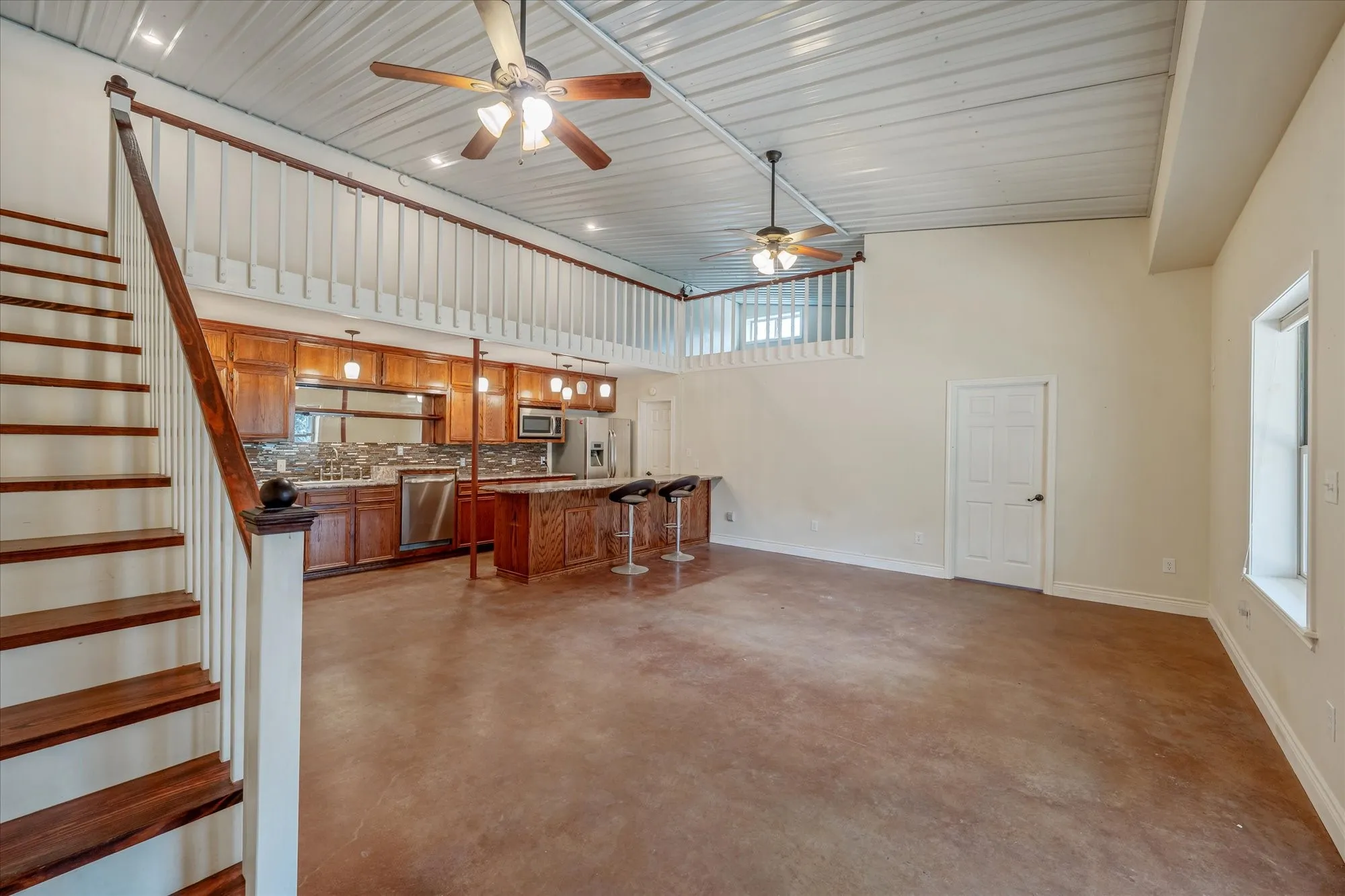 Living room with concrete floors, a ceiling fan, a high ceiling, and plenty of natural light