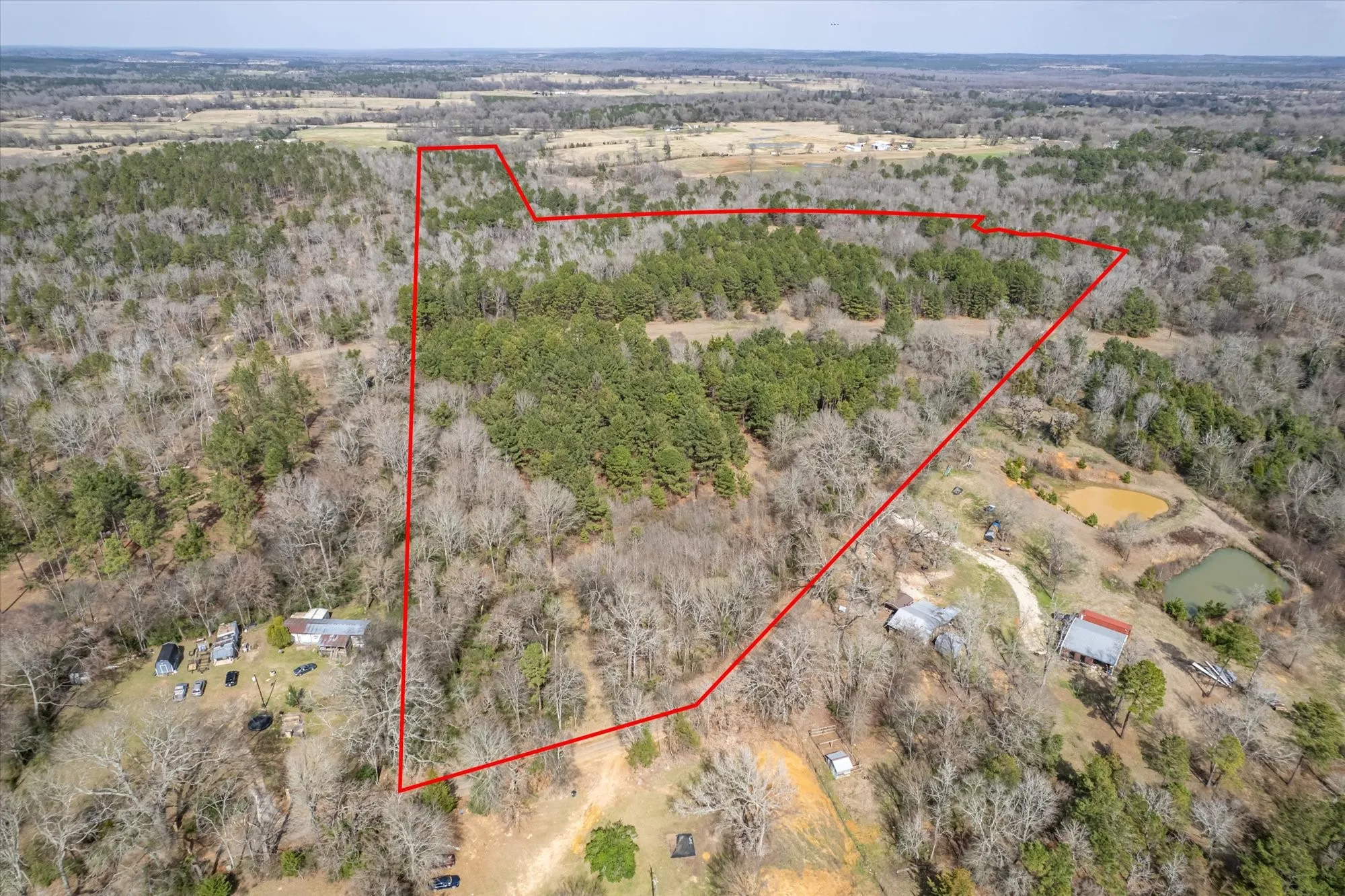 Aerial overview of property's location with a heavily wooded area and property parcel outlined