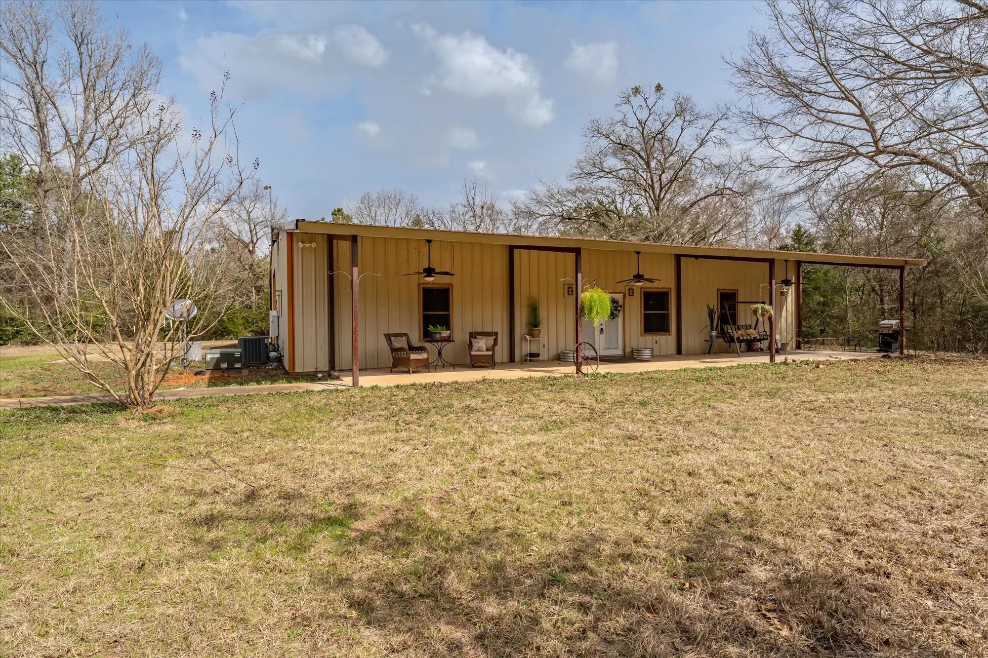 front view of house featuring a lawn, a ceiling fan, board and batten siding, and a patio