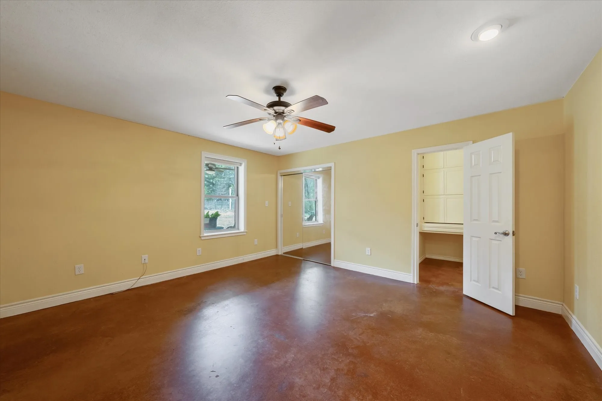 Unfurnished bedroom featuring finished concrete floors, a ceiling fan, and a closet