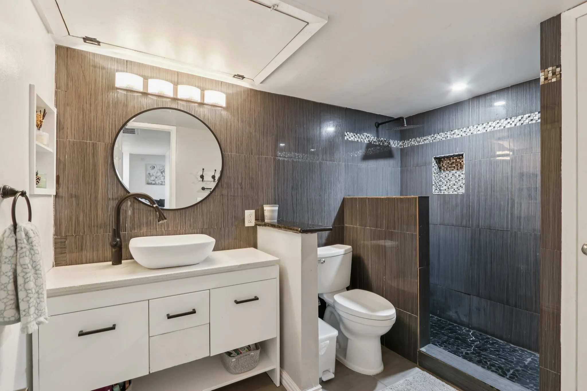 Bathroom featuring vanity, a walk in shower, and tile walls