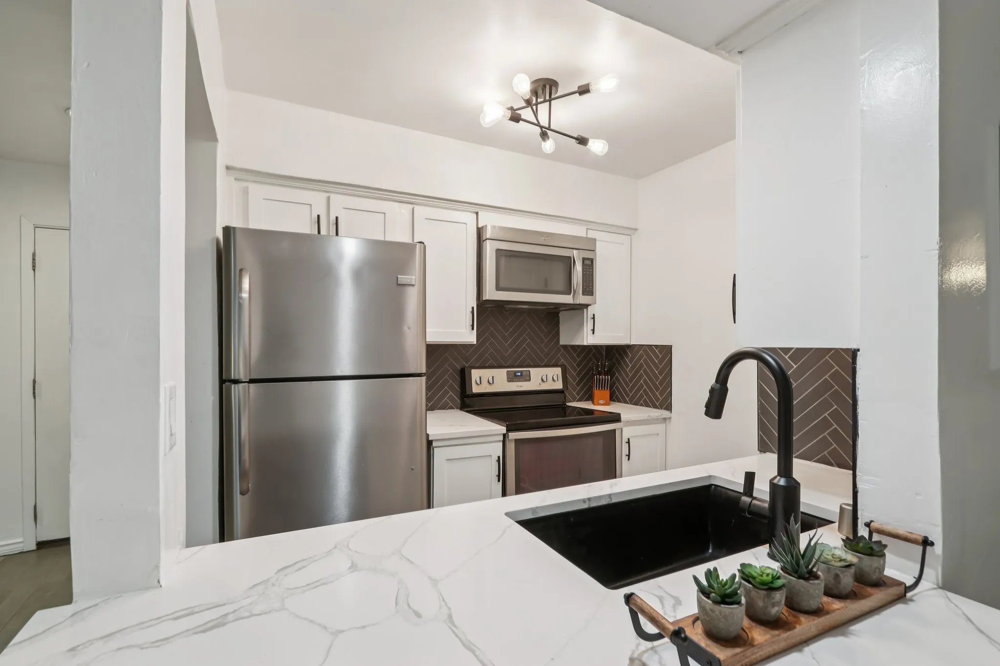 Kitchen featuring stainless steel appliances, white cabinetry, backsplash, and light stone counters- Refrigerator to stay
