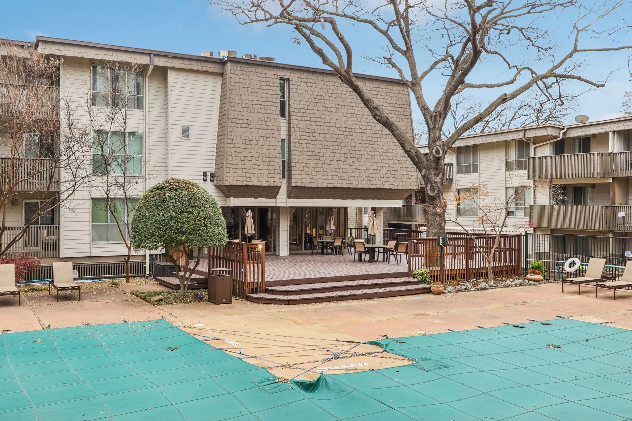 Back of property featuring a community pool, a wooden deck, and a patio