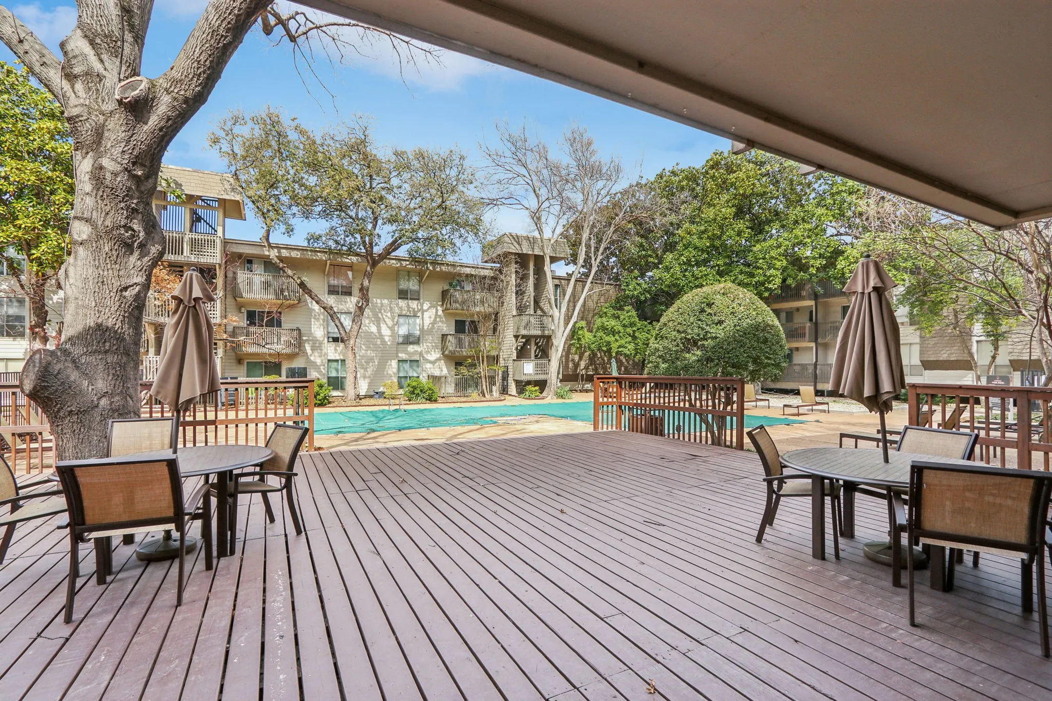Wooden deck with outdoor dining space, a community pool, and a patio