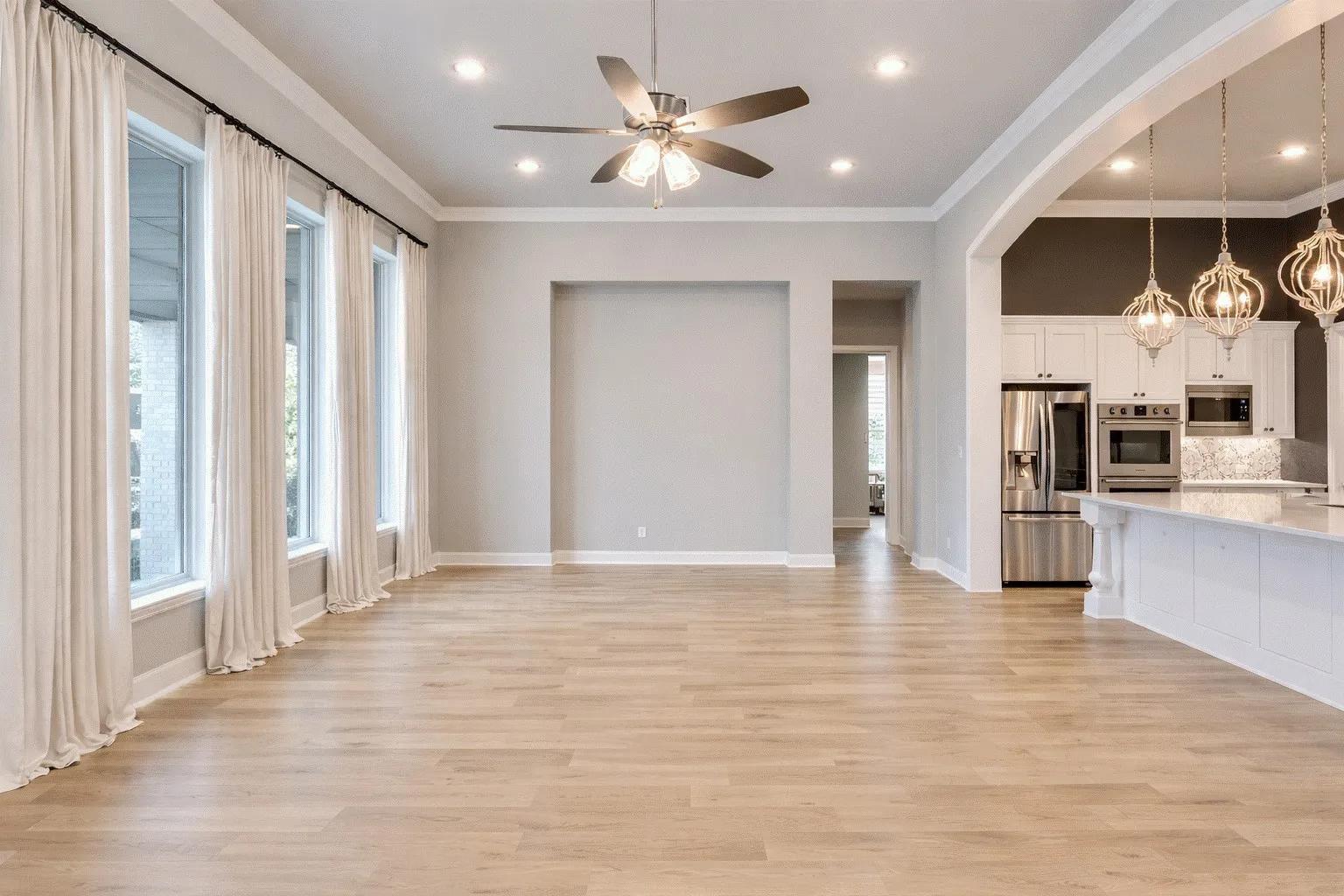 Unfurnished living room with ceiling fan, light wood-style floors, crown molding, arched walkways, and hanging lights