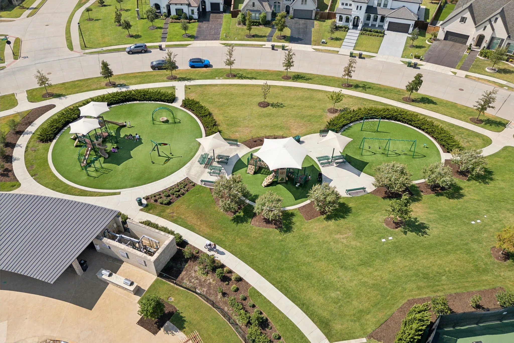Expansive community park featuring multiple play structures, swings, shade canopies, and picnic tables