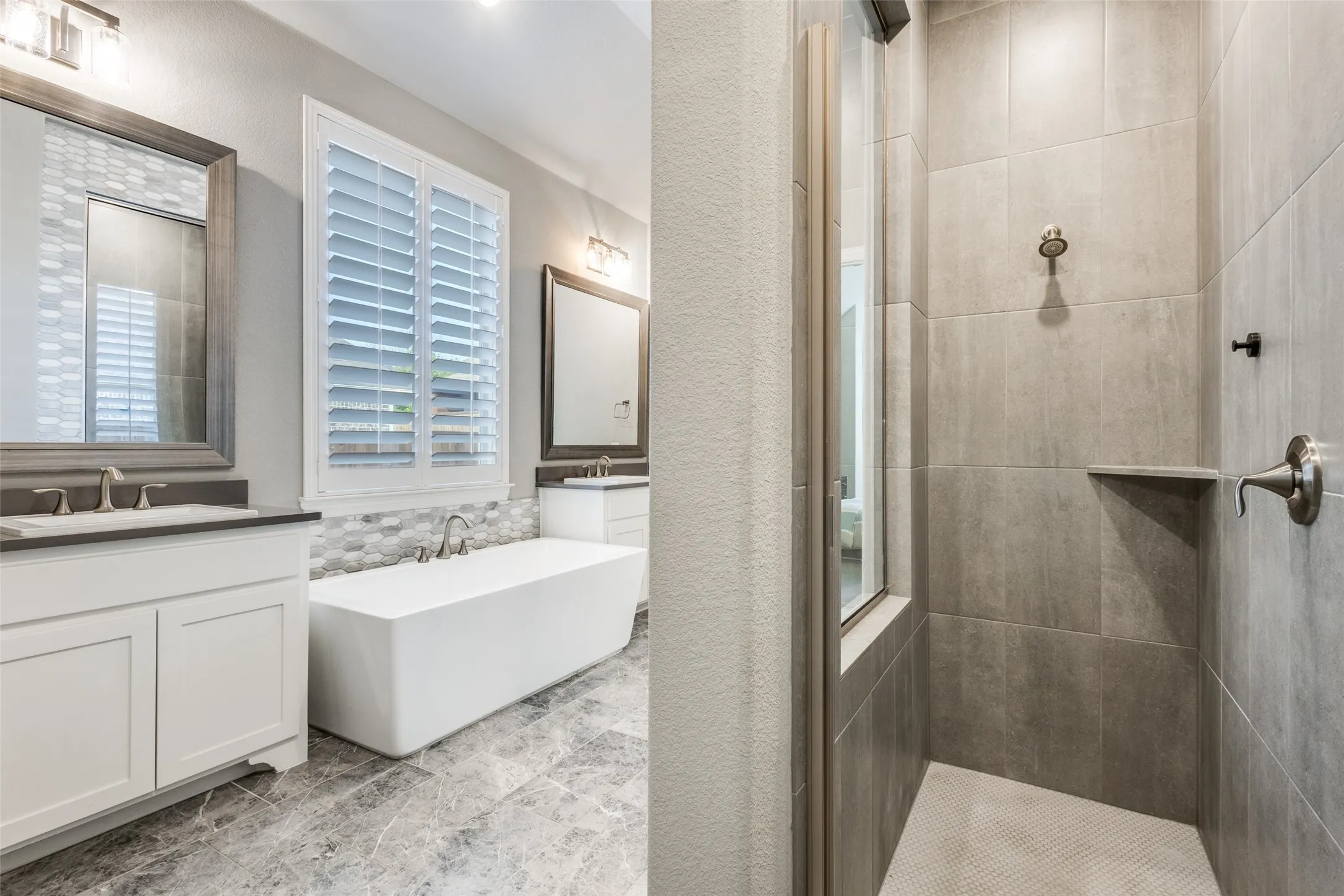 Full bath with walk in shower, two vanities, a soaking tub, and tile walls