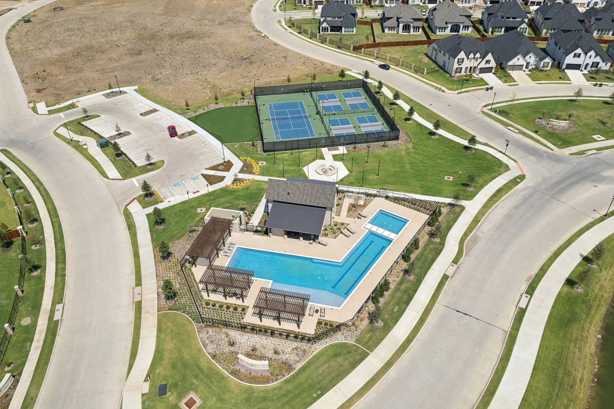 Community recreational area featuring a large swimming pool, multiple shaded pergolas, and an adjacent tennis court complex