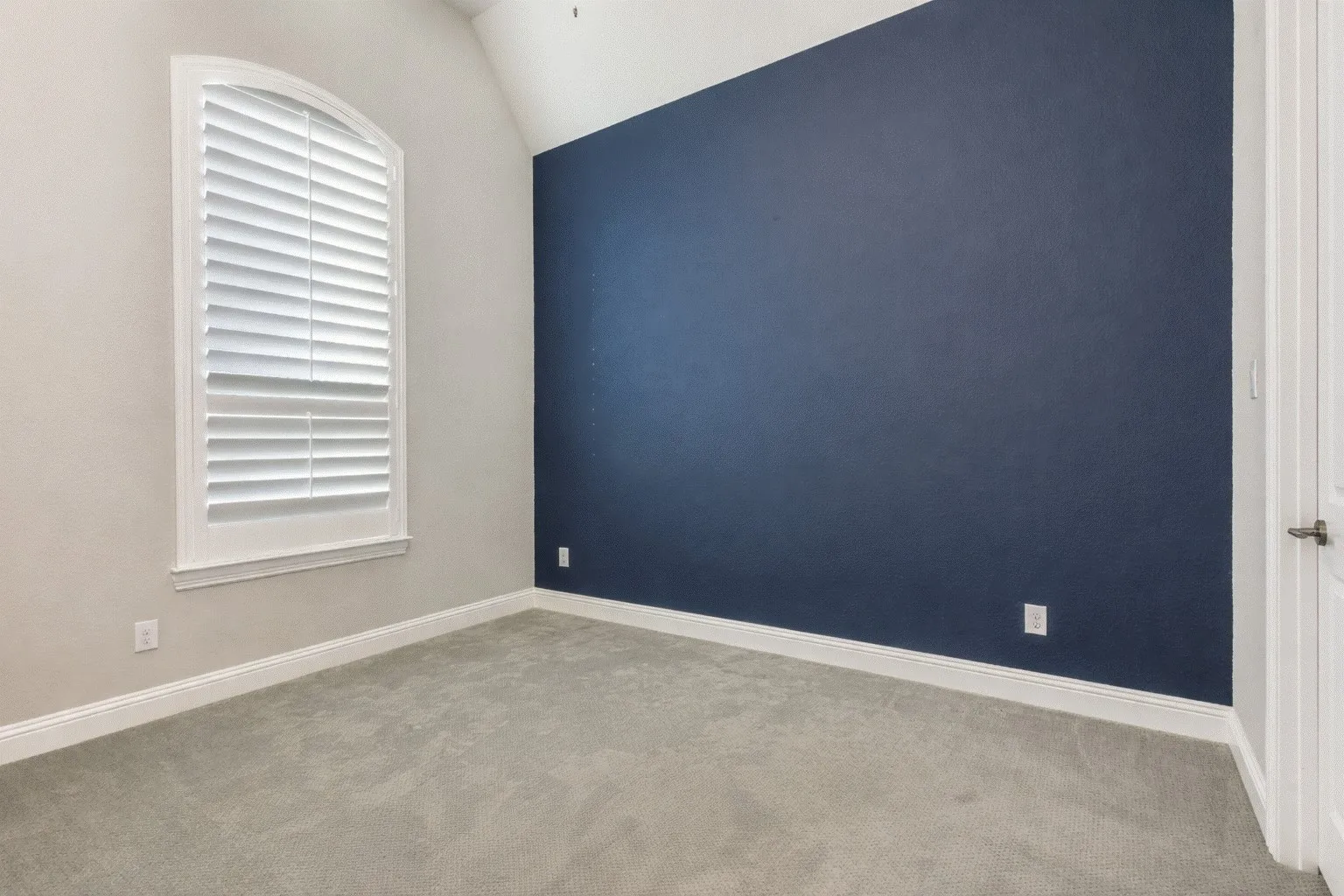 Empty room with light colored carpet and vaulted ceiling