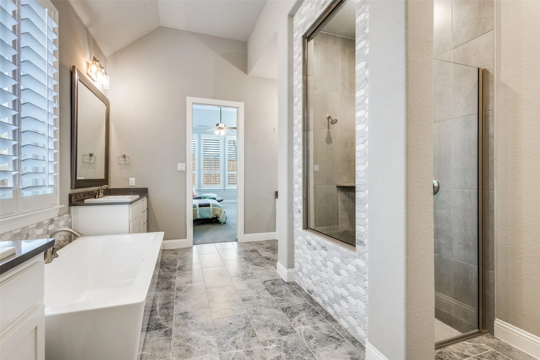 Ensuite bathroom with vanity, a stall shower, vaulted ceiling, a freestanding bath, and ceiling fan