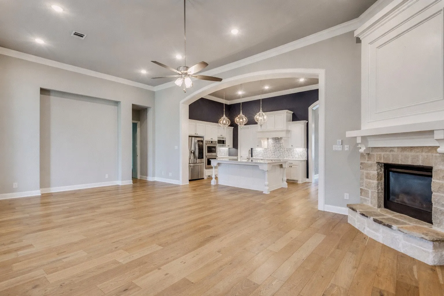 Unfurnished living room with a fireplace, a ceiling fan, light wood-type flooring, ornamental molding, and recessed lighting