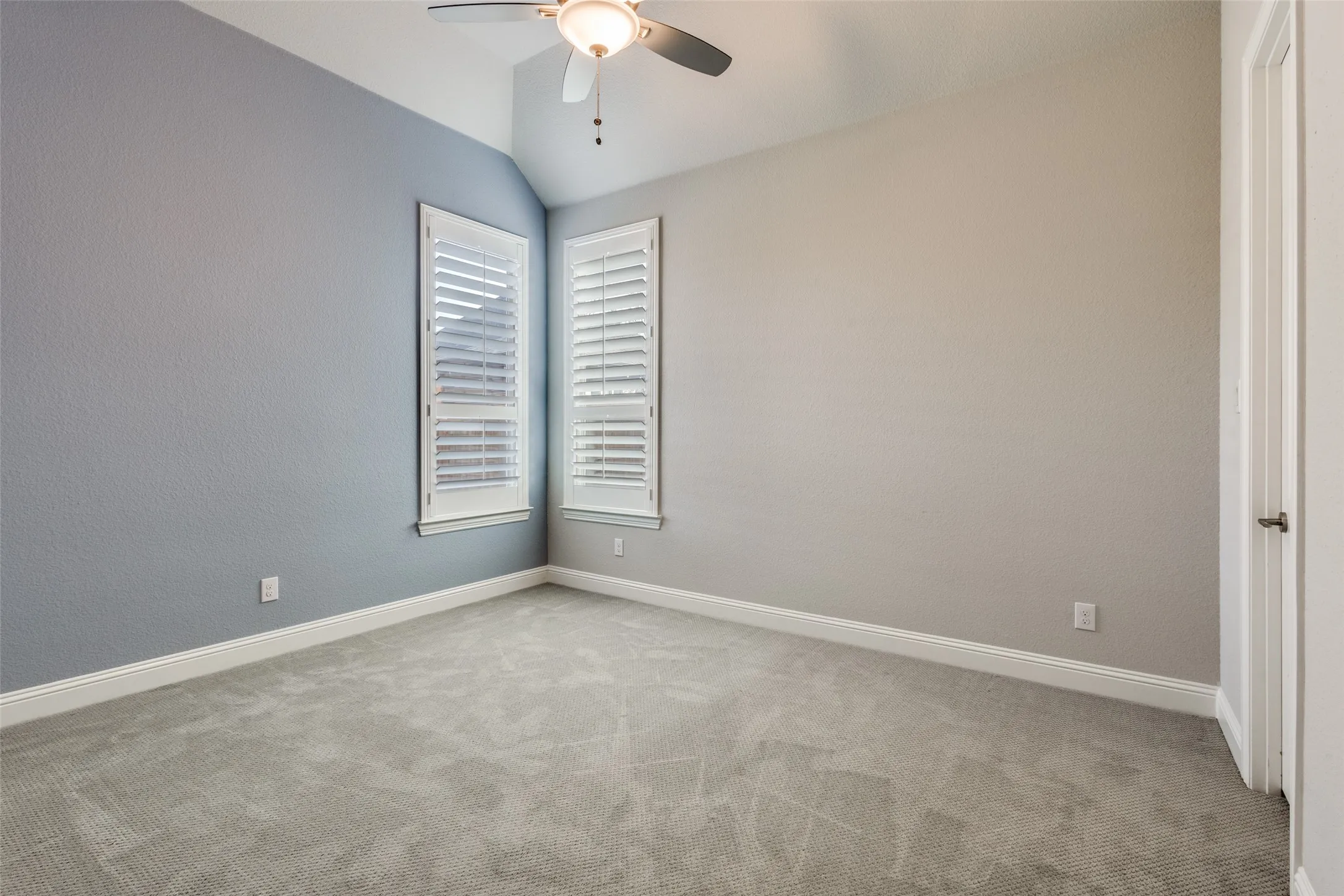Empty room featuring lofted ceiling, light carpet, and a ceiling fan